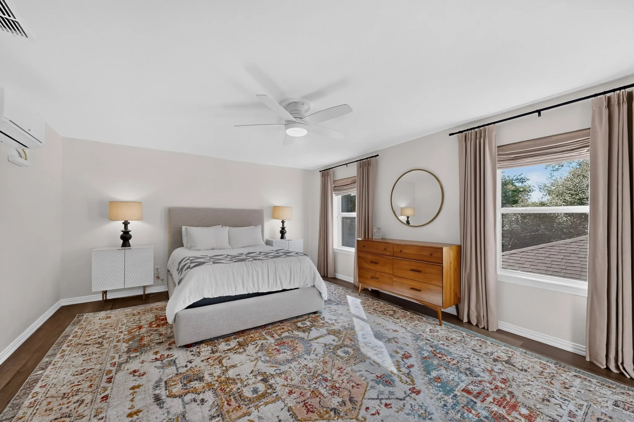 Wood-finish flooring, ceiling fan, split air conditioning unit, and multiple windows with privacy blinds