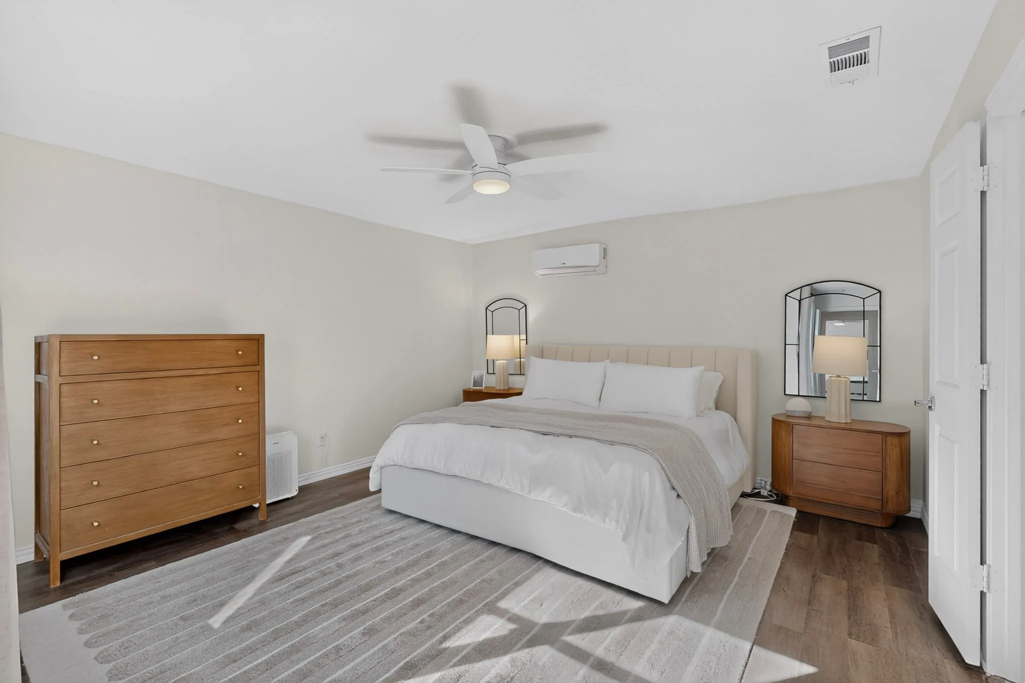 Wood-finish flooring with light-toned walls, featuring a ceiling fan with integrated lighting