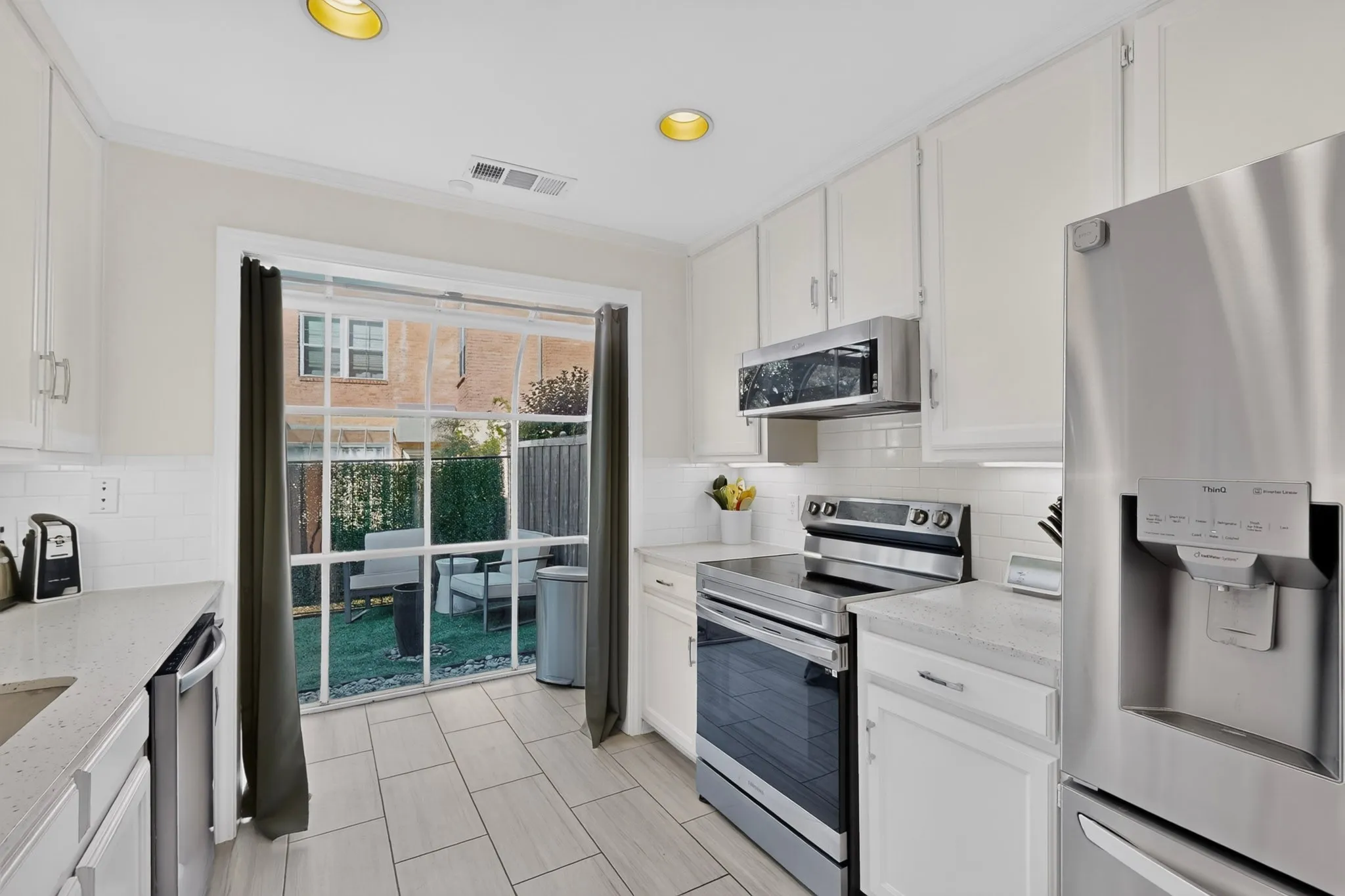 Kitchen featuring white cabinetry, light-colored countertops, stainless steel appliances, and tile flooring
