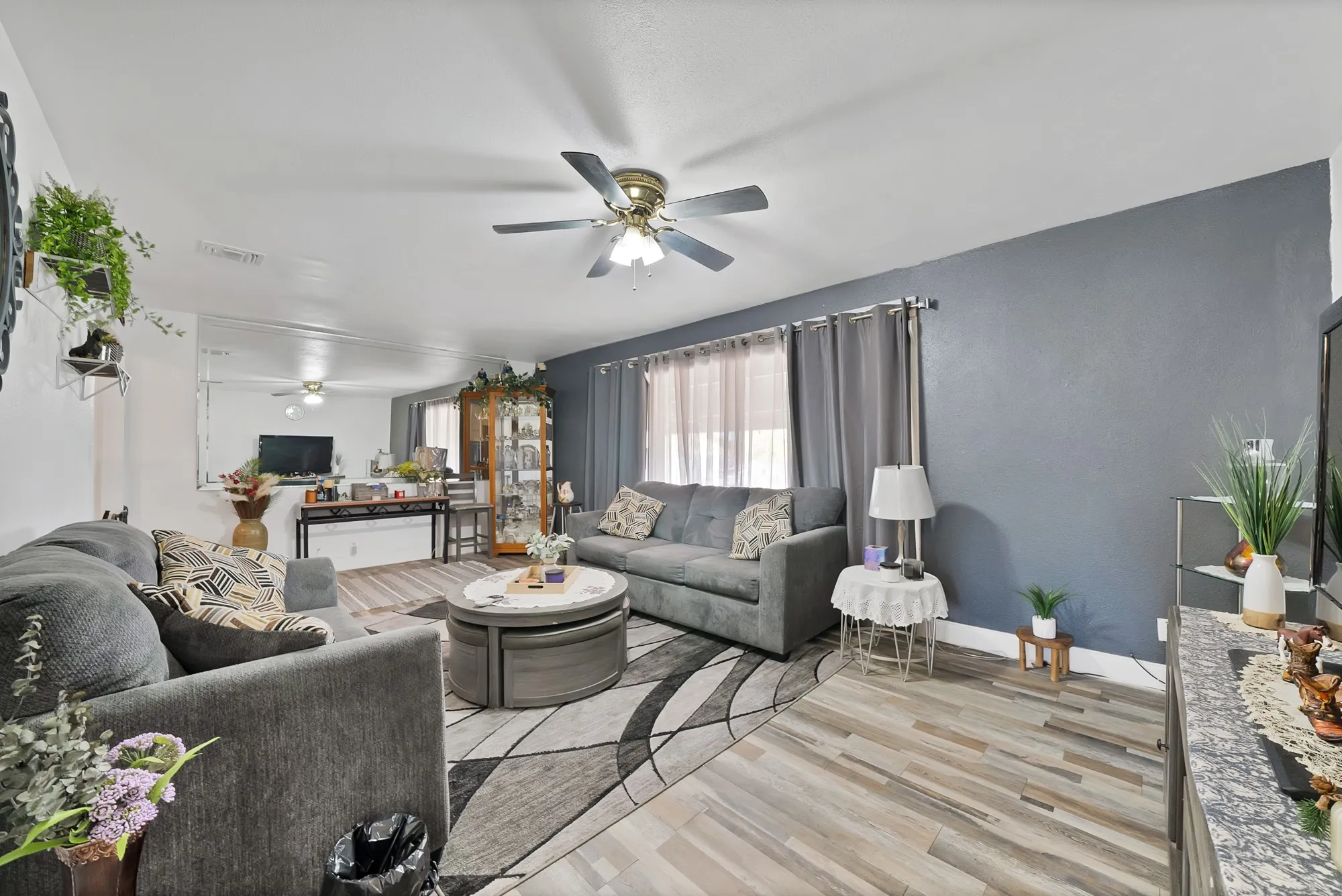Living area featuring wood-finish flooring, a ceiling fan, and a neutral color palette