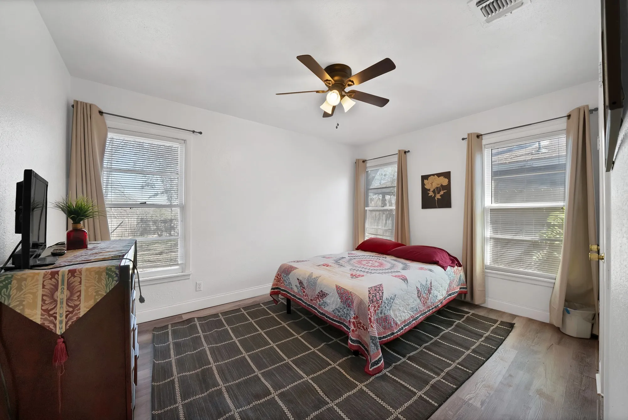 Wood-finish flooring, white walls, and a ceiling fan with integrated lighting