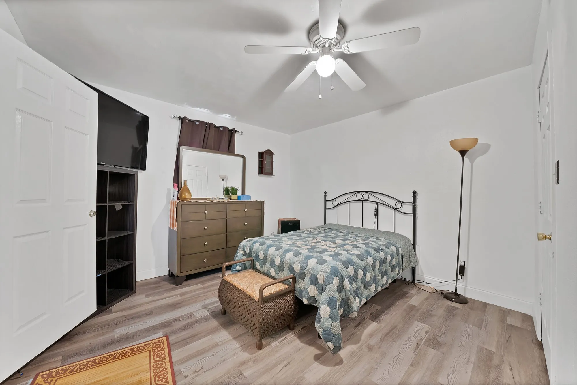 Wood-finish flooring throughout, bright white walls, and a ceiling fan with integrated lighting