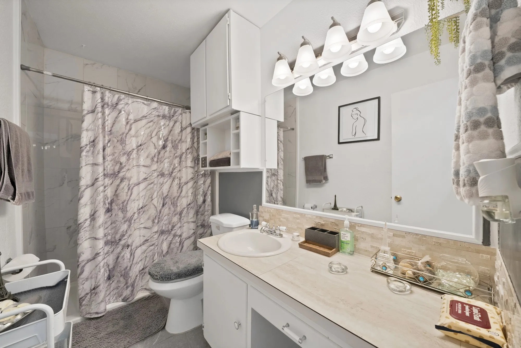 White vanity with a laminate countertop, integrated sink, and chrome fixtures