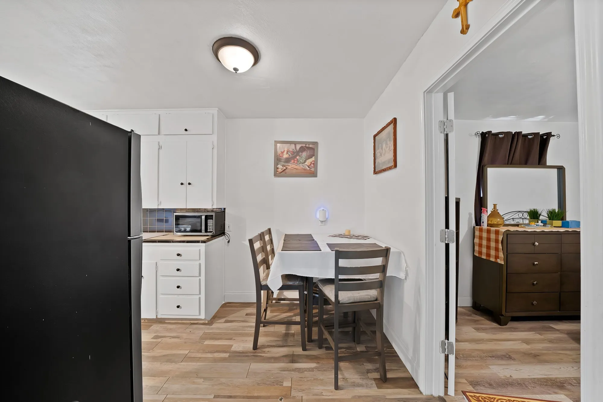 Bright dining area with wood-finish flooring, a dedicated workspace with built-in desk cabinetry, and access to adjoining bedroom