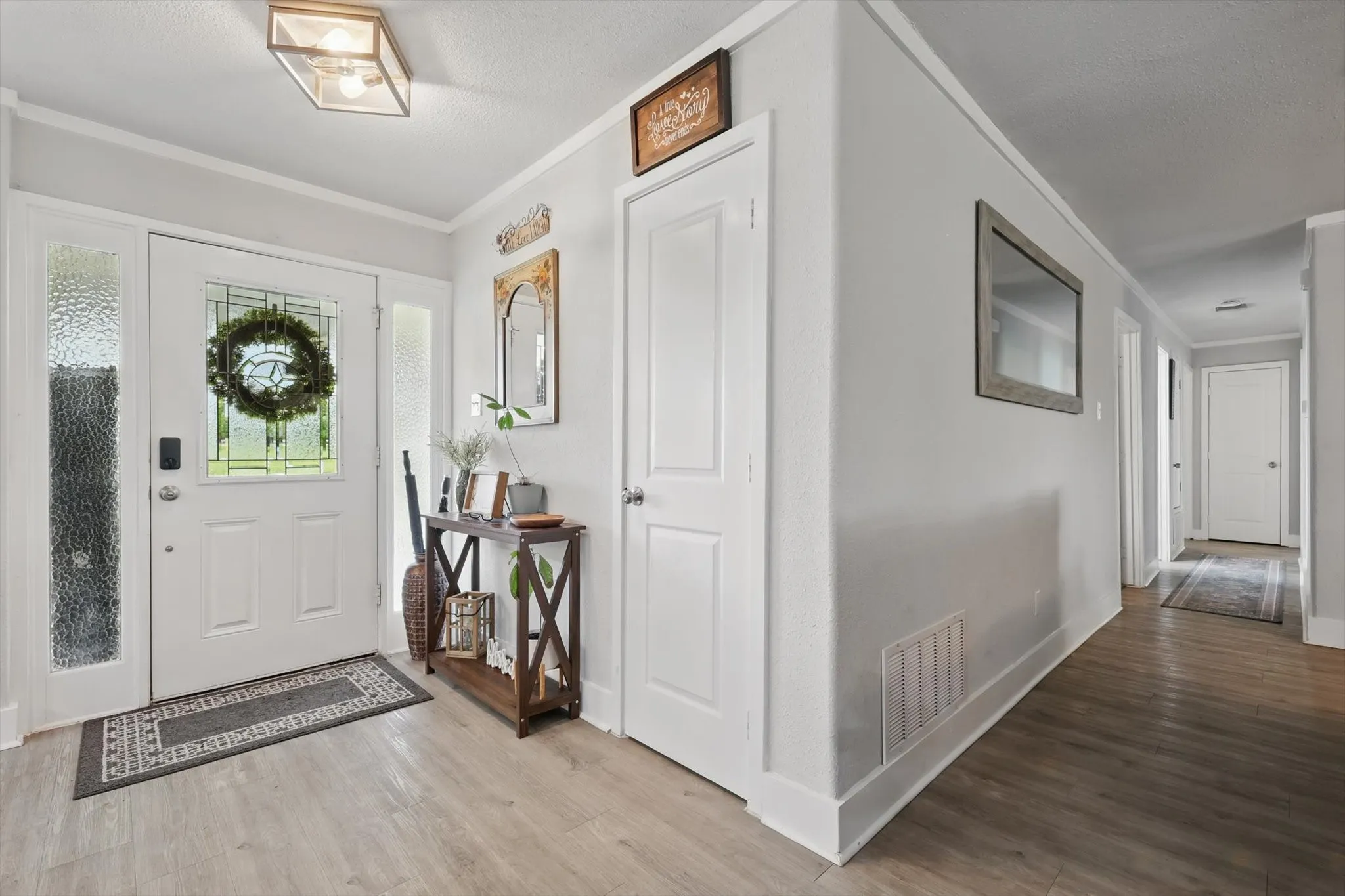 Entryway featuring wood-finish flooring, white paneled doors, and a decorative glass front door with sidelights