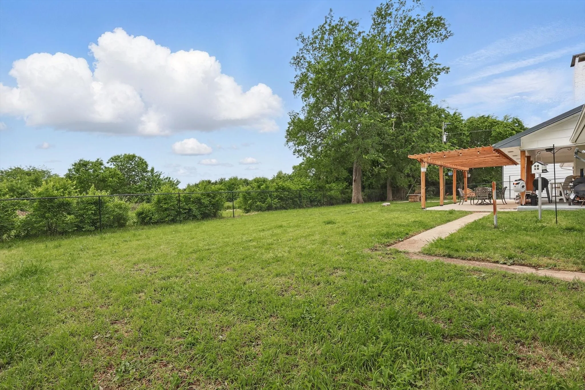 Expansive lawn featuring mature trees and a perimeter fence