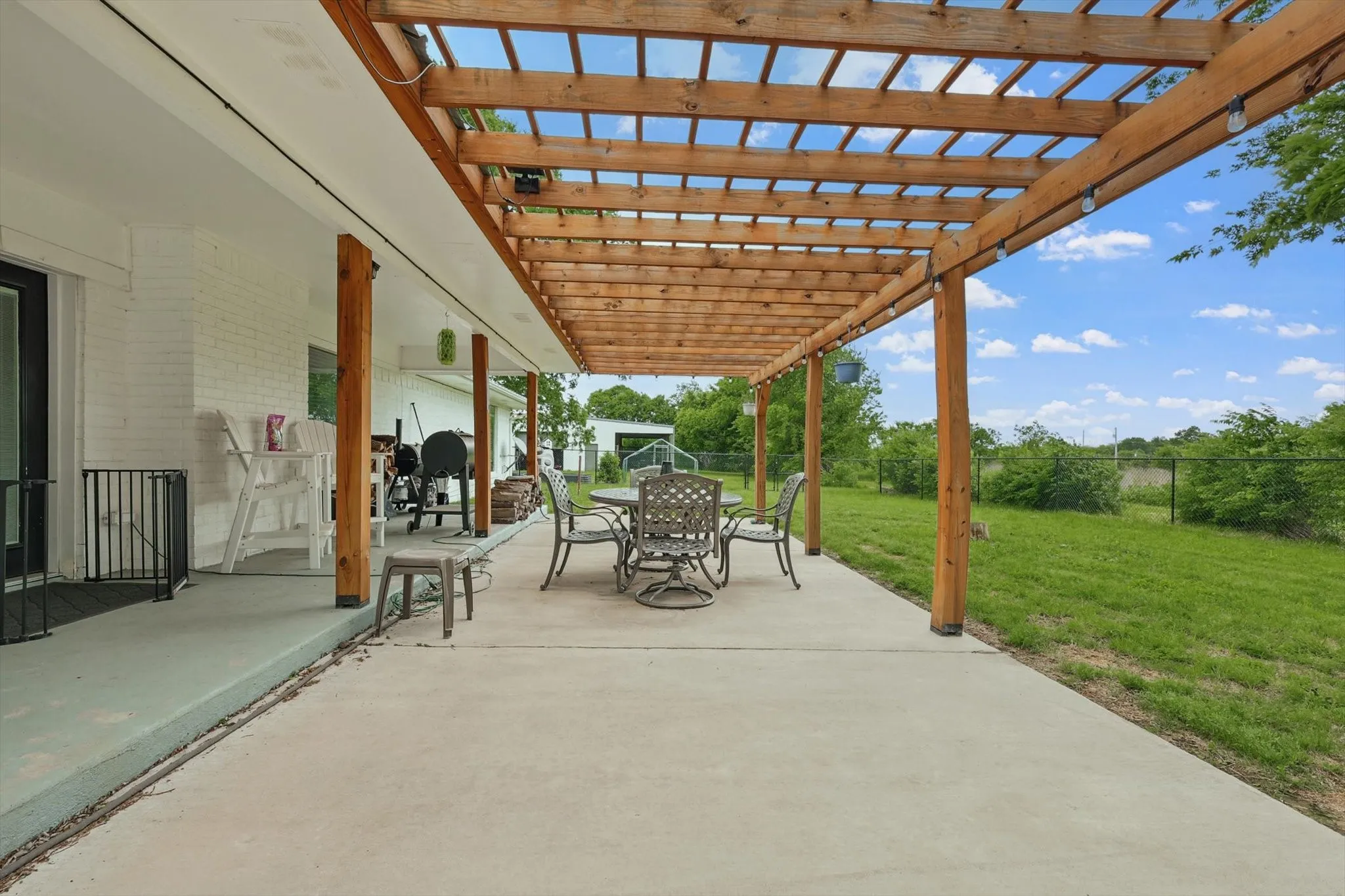 Expansive concrete patio with a wooden pergola