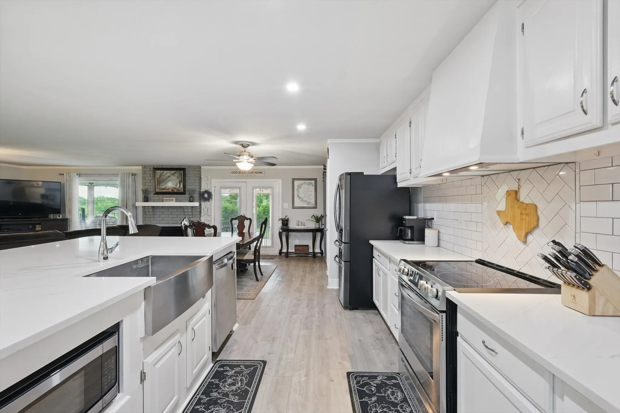 Kitchen featuring white cabinetry, light countertops, wood-finish flooring, and subway tile backsplash