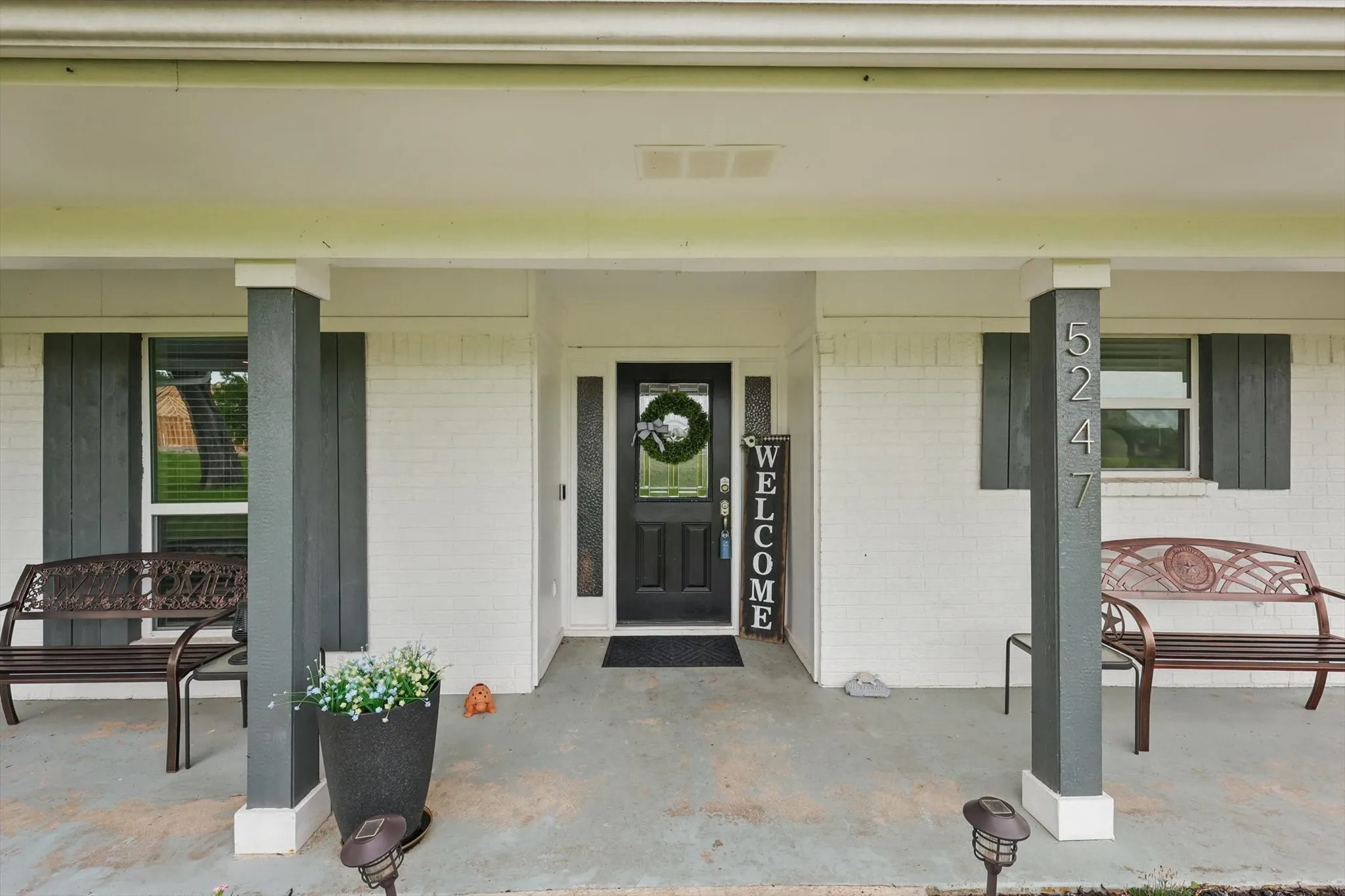 Brick facade with painted shutters, covered entry porch, and glass panel entry door