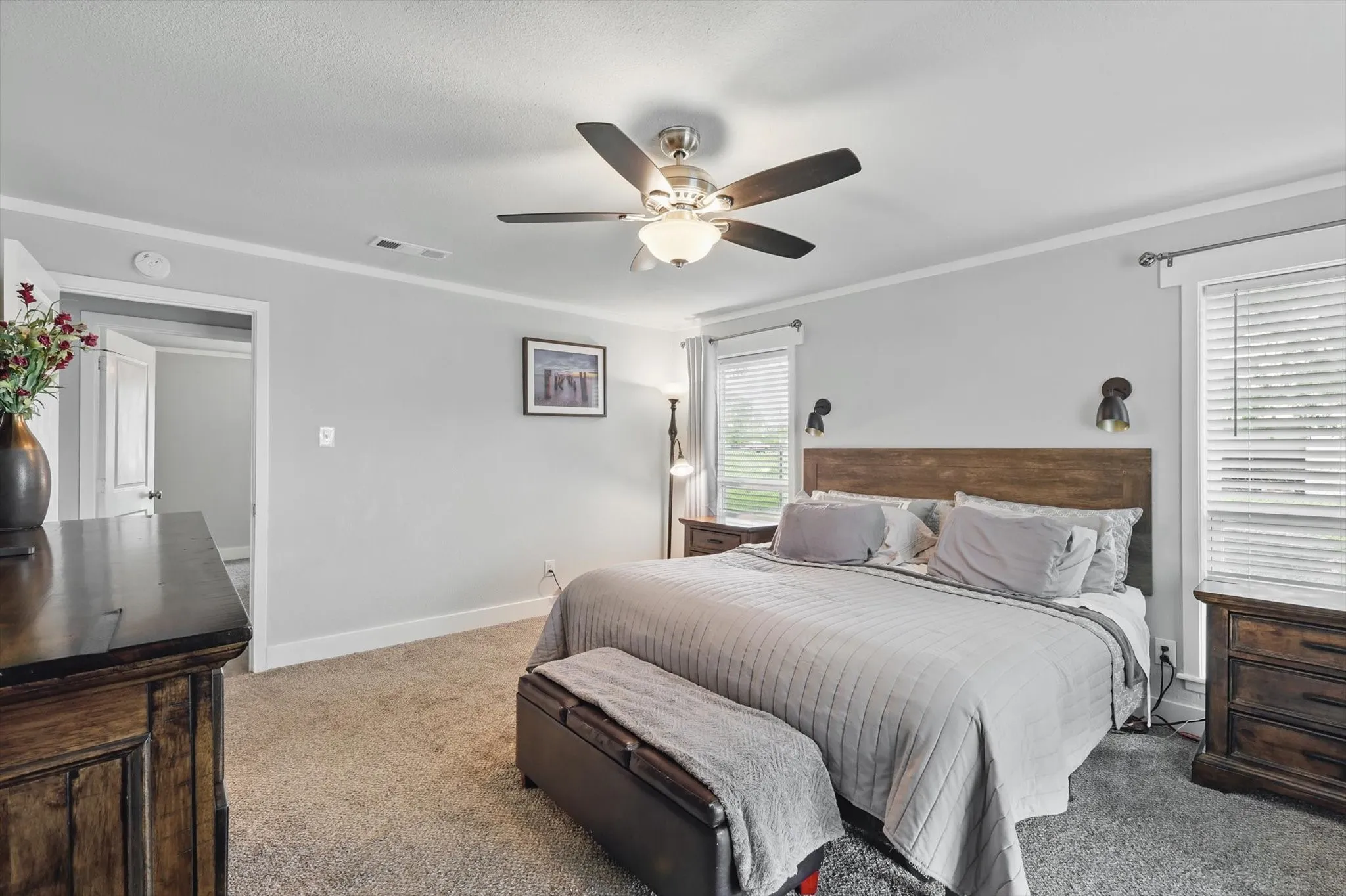 Neutral wall paint, crown molding, ceiling fan with integrated lighting, two windows with blinds, and carpeted flooring