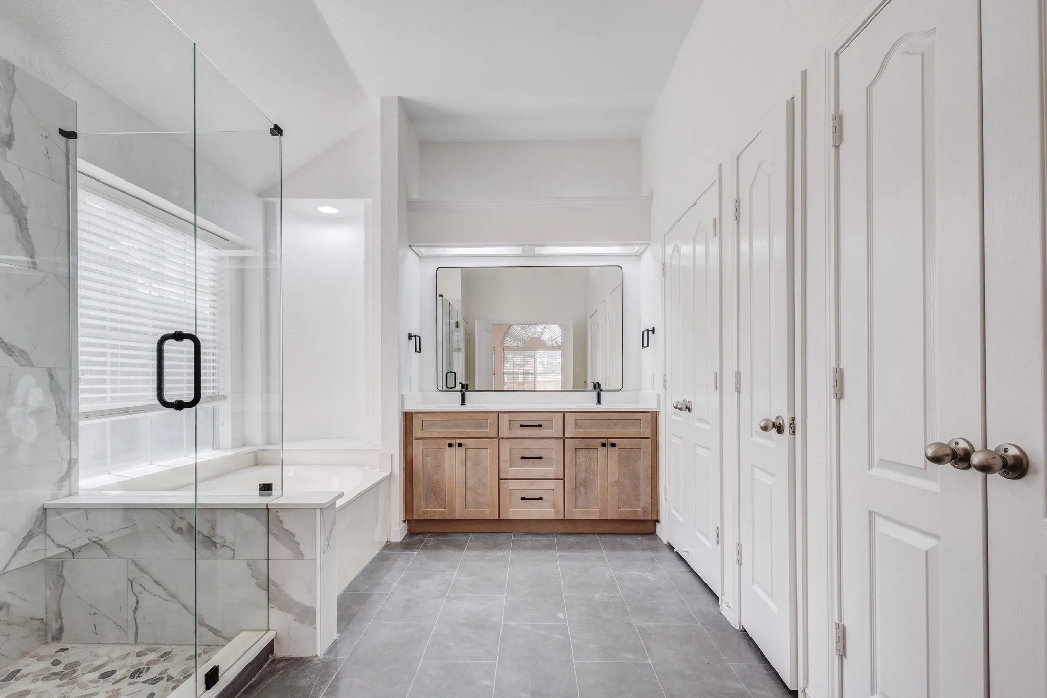 Bathroom featuring tile patterned flooring, dual bowl vanity, and separate shower and tub