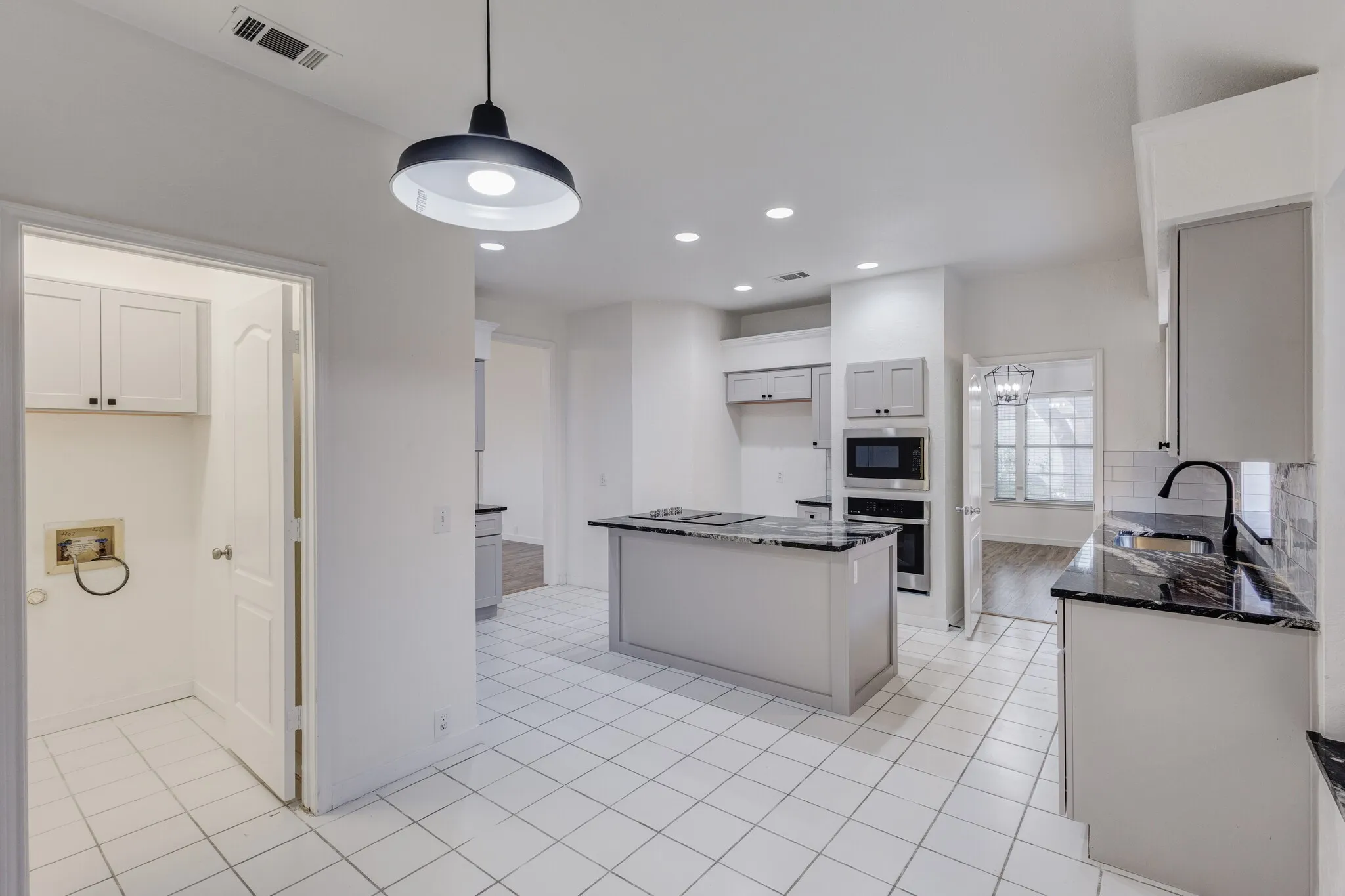Kitchen featuring appliances with stainless steel finishes, sink, pendant lighting, light hardwood / wood-style floors, and a kitchen island