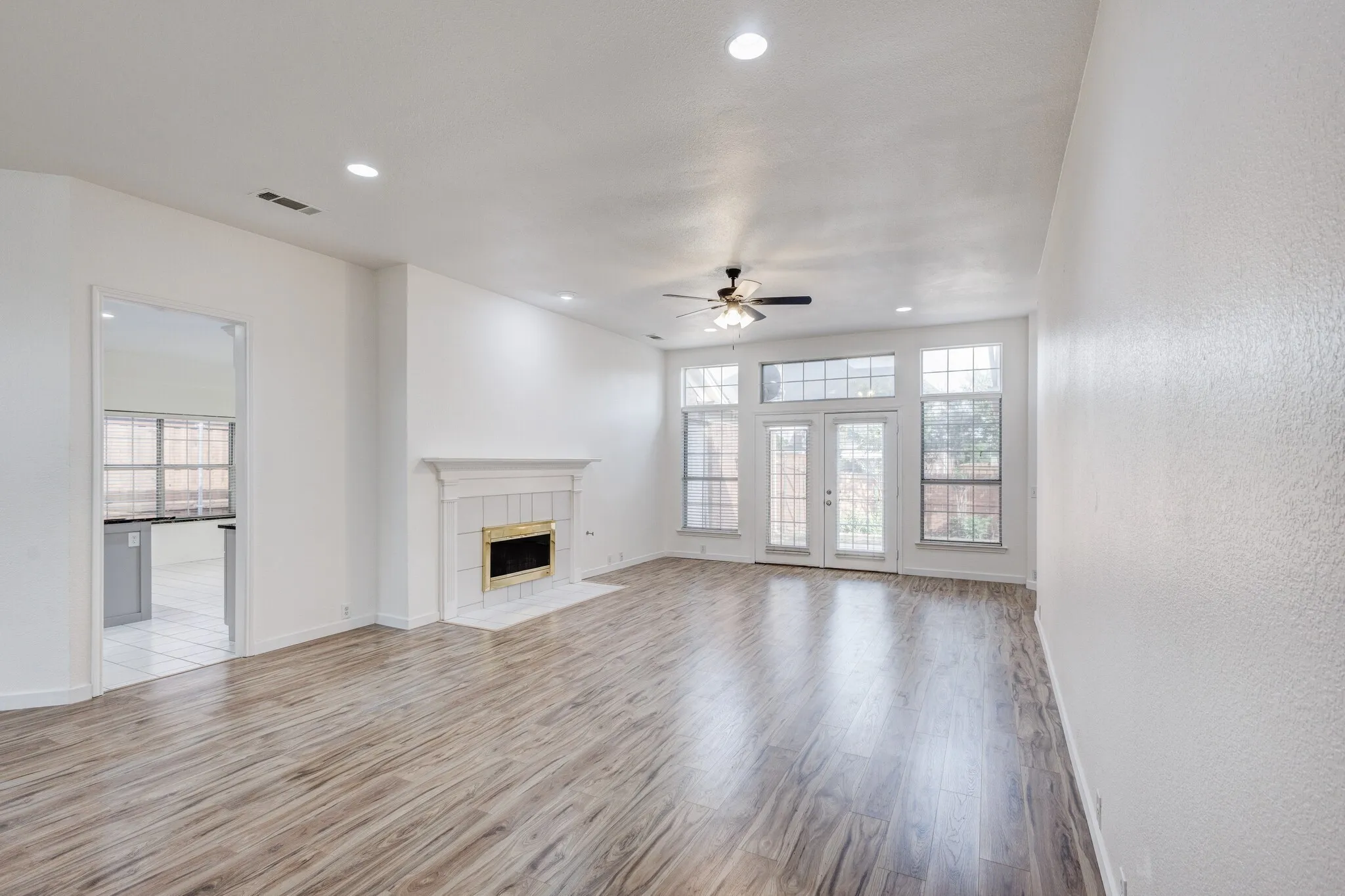 Unfurnished living room featuring a tile fireplace, ceiling fan, and light hardwood / wood-style floors