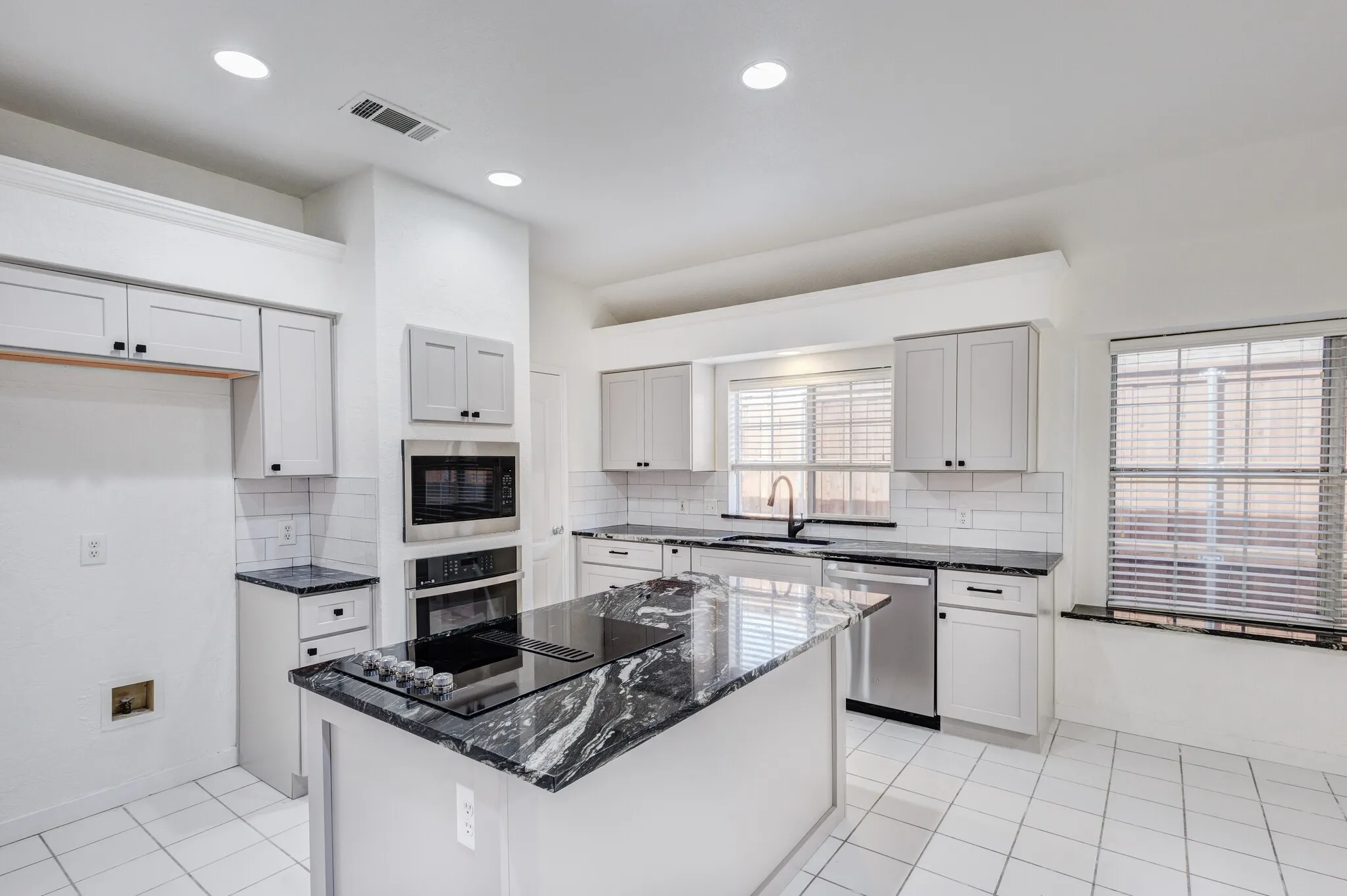 Kitchen featuring a center island, black appliances, backsplash, and light tile patterned floors