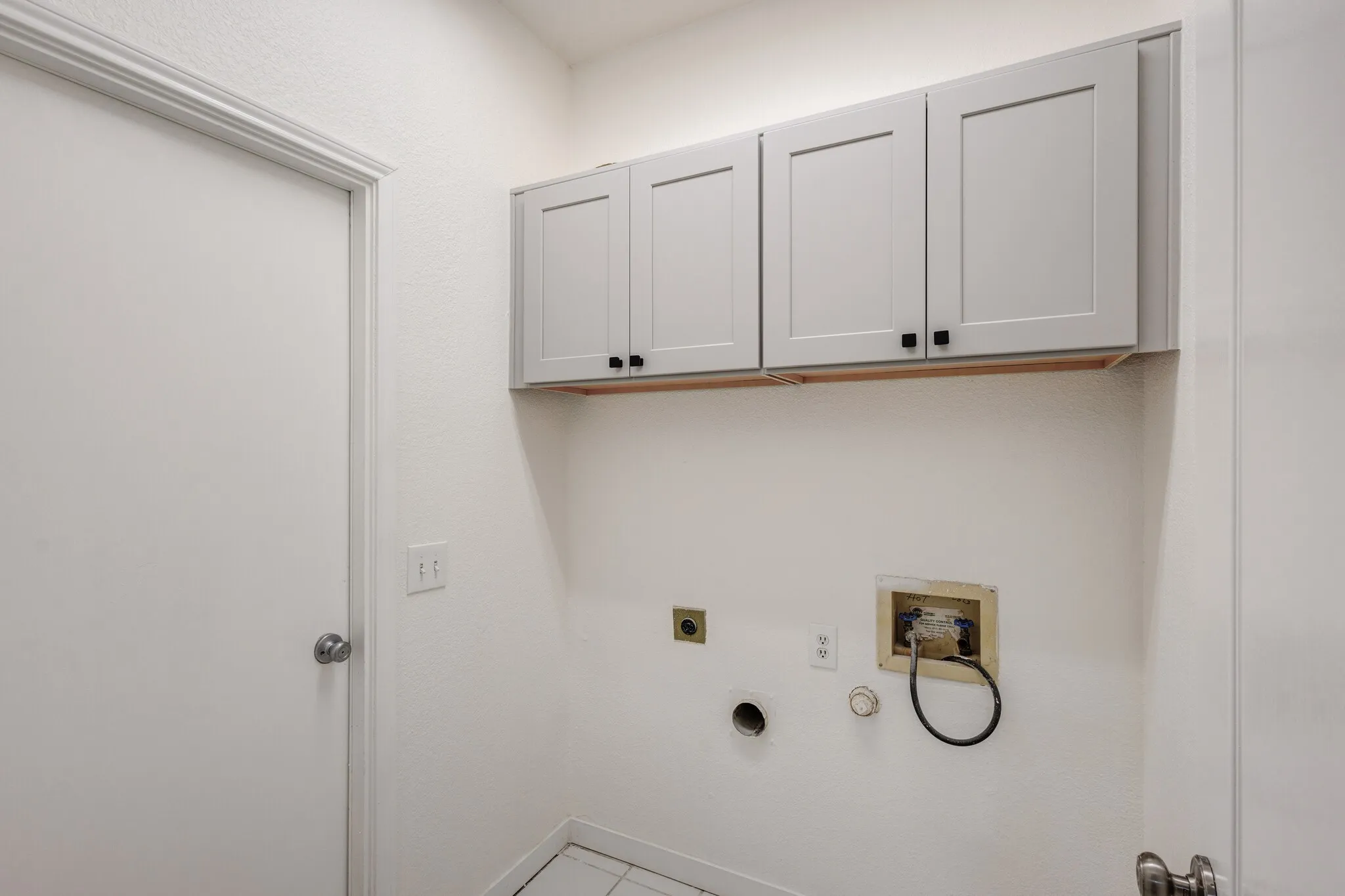 Laundry room featuring hookup for an electric dryer, gas dryer hookup, hookup for a washing machine, tile patterned floors, and cabinets