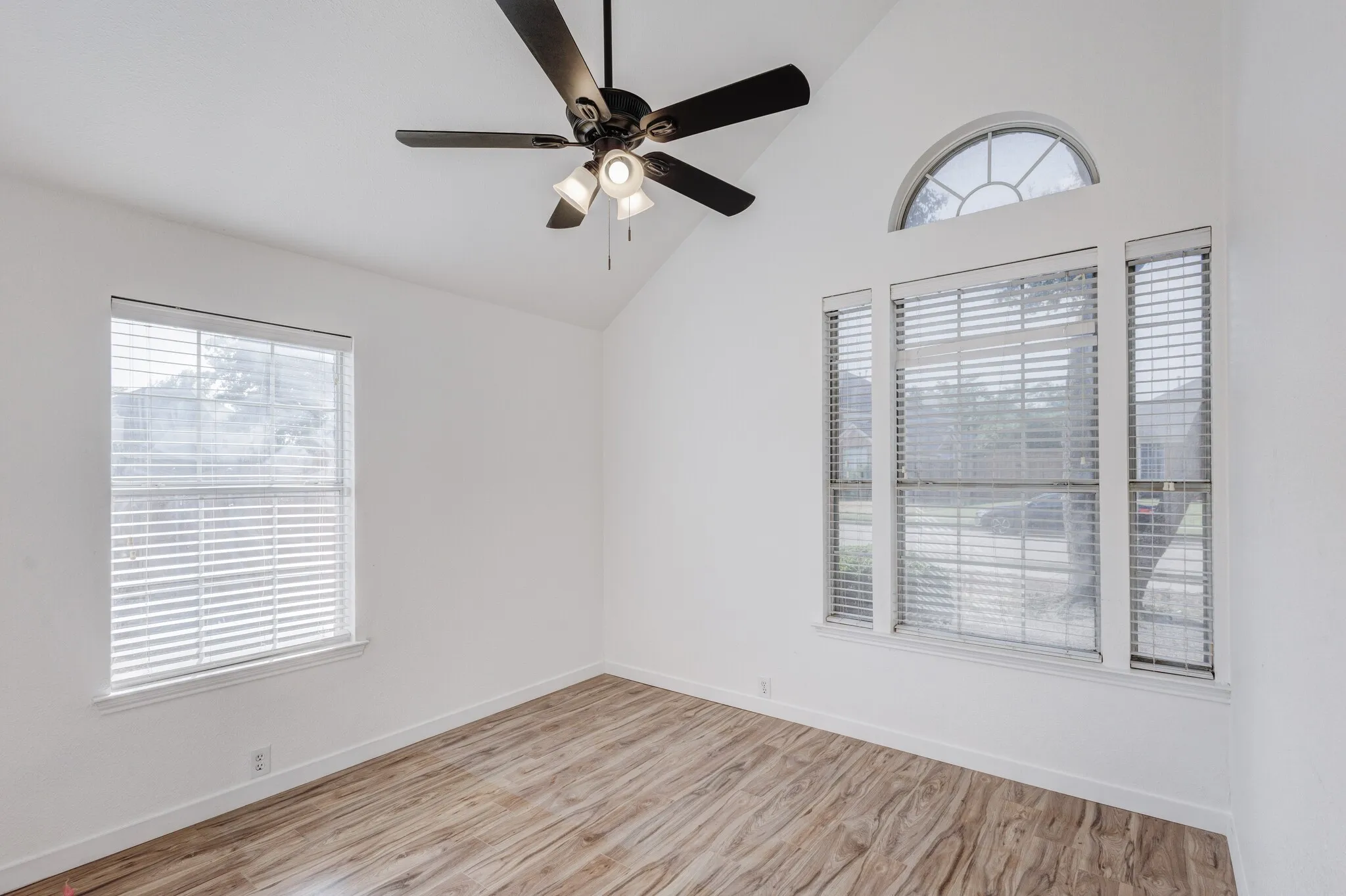 Empty room with light hardwood / wood-style flooring, ceiling fan, and vaulted ceiling