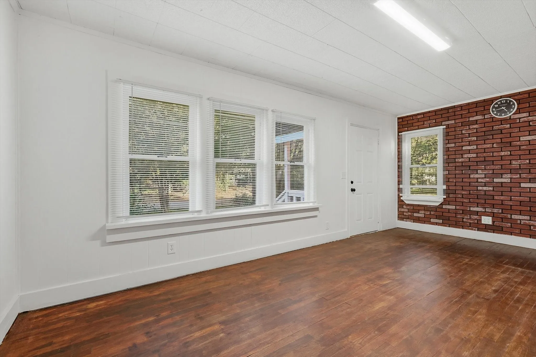Wood-finish flooring, white walls, and a prominent brick accent wall
