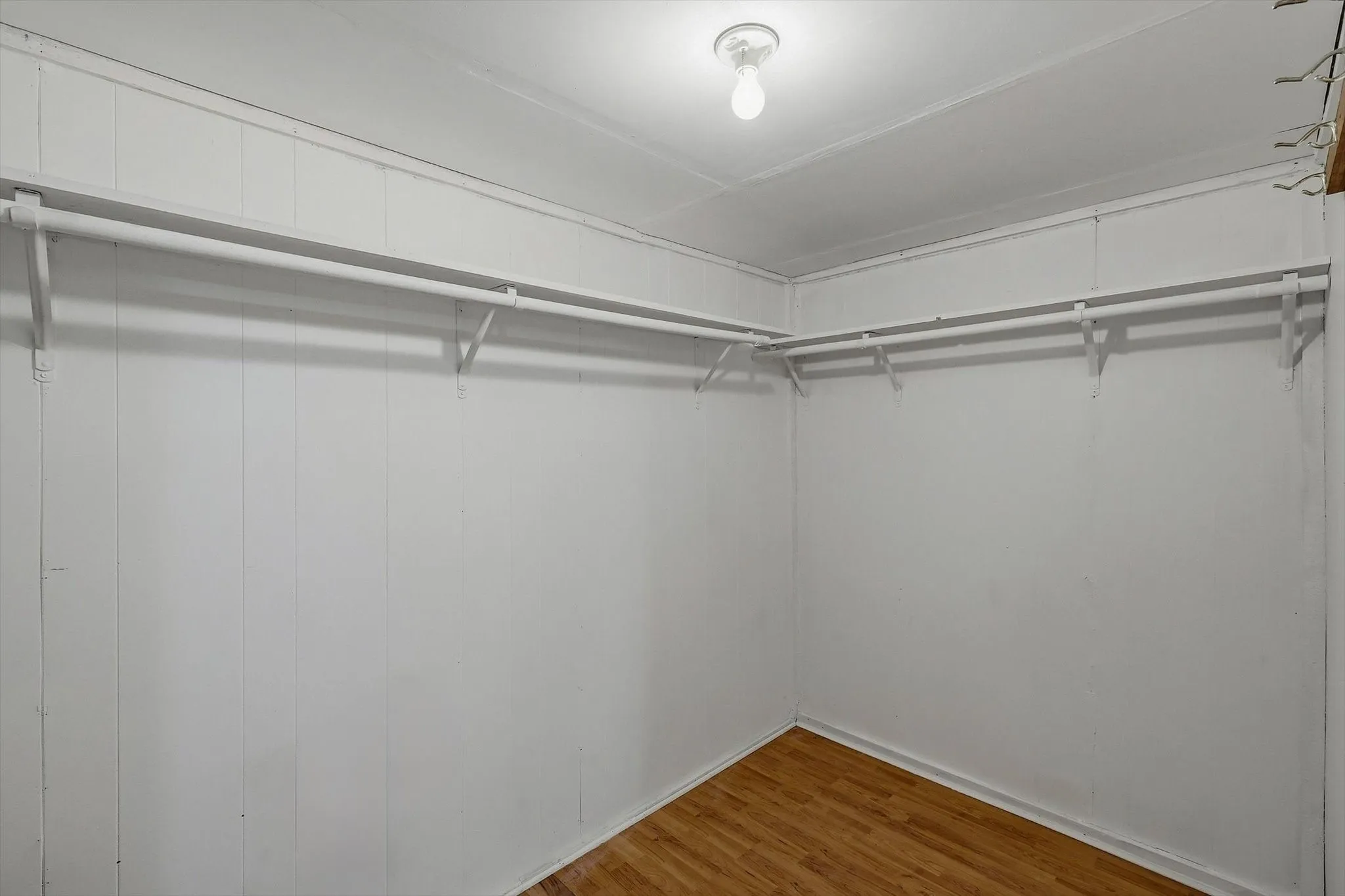 Built-in closet shelving and hanging rods with wood-finish flooring