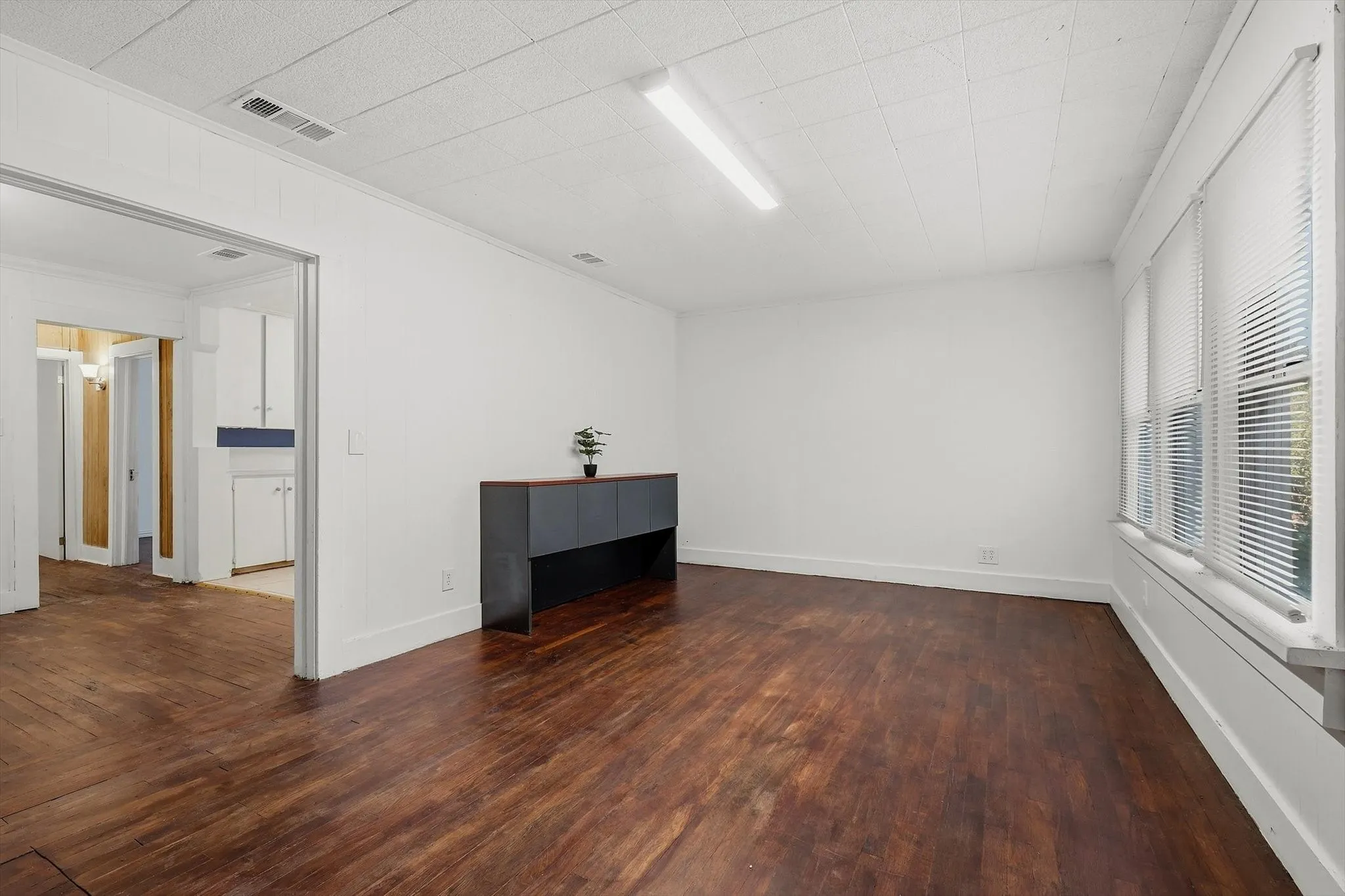 Wood-finish flooring, white walls, and multiple windows with blinds