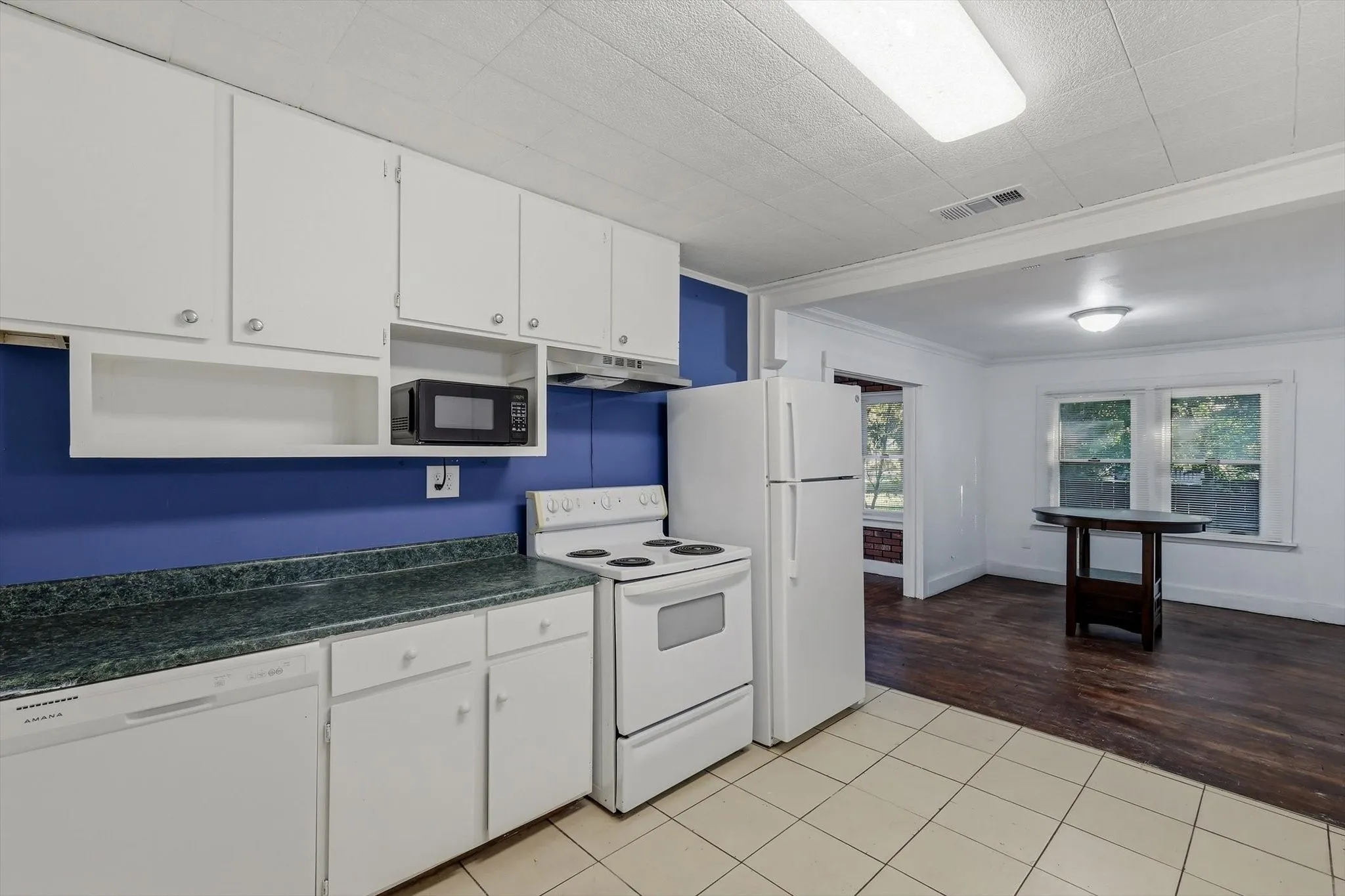 Kitchen with white cabinetry, a built-in microwave shelf, and durable countertops