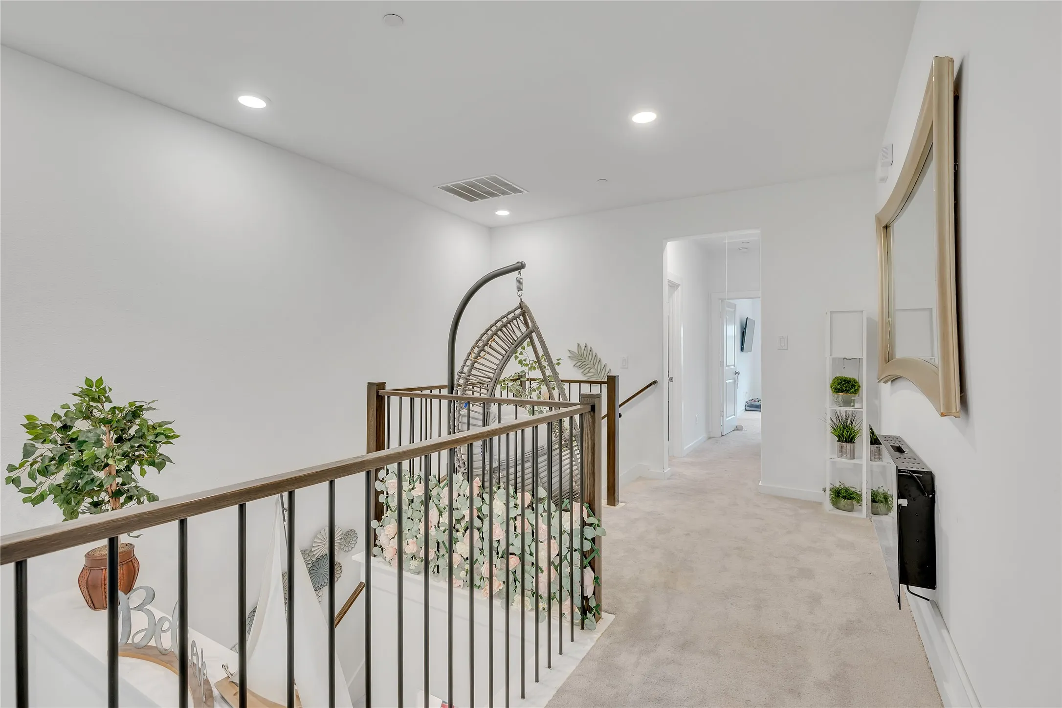 Hallway featuring light-colored carpeting, recessed lighting, and a wood-toned railing with black balusters