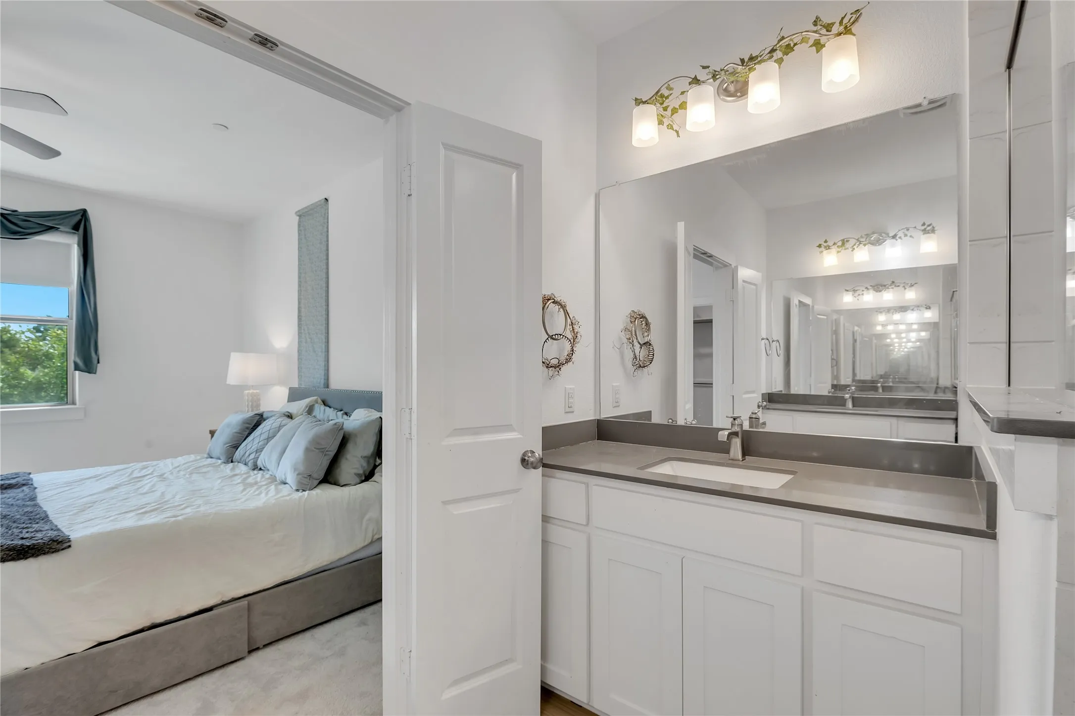 Bathroom vanity featuring a single basin, grey countertop, and white cabinetry
