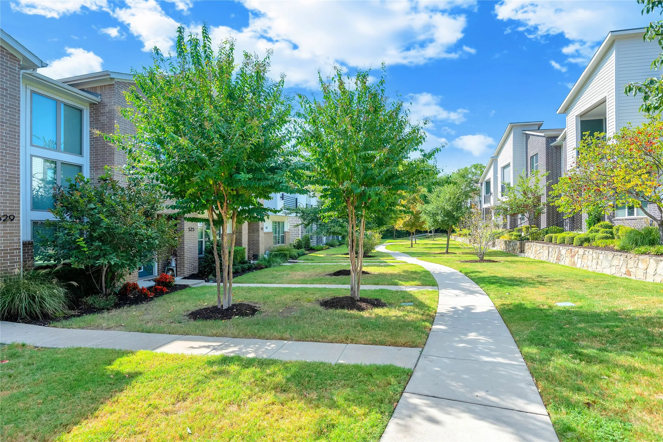 Manicured green spaces with mature trees and a curving concrete pathway