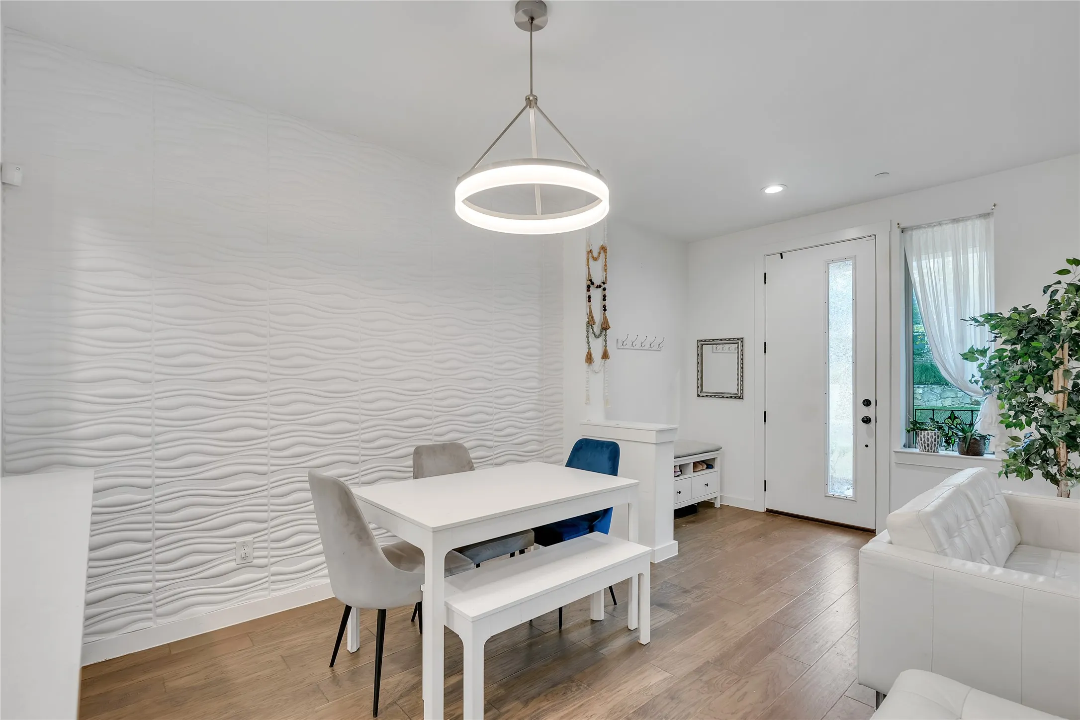 Wood-finish flooring, textured accent wall, recessed lighting, and a modern circular pendant light