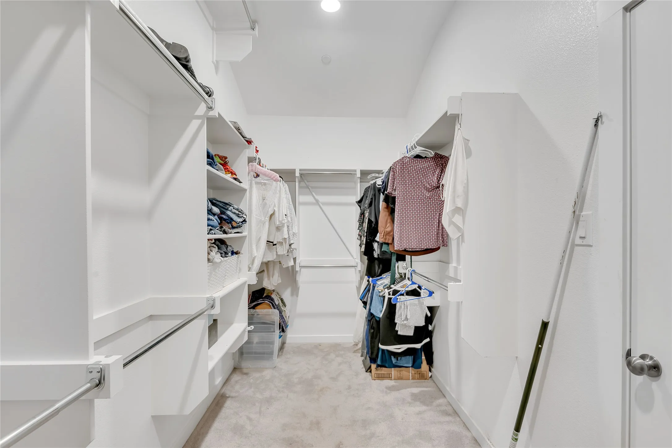 Walk-in closet with built-in shelving, chrome hanging rods, and recessed lighting