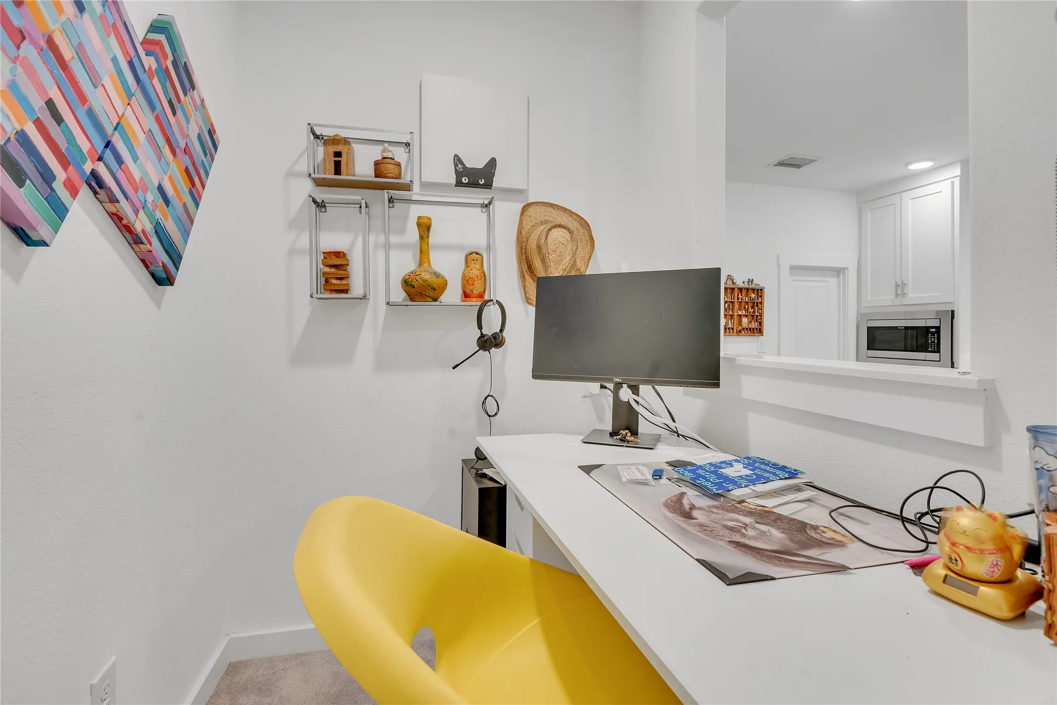 Built-in desk with a white finish, featuring a pass-through window and recessed lighting in the adjacent space