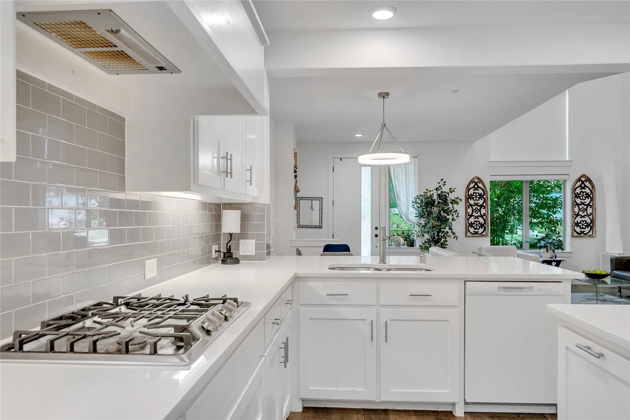 Kitchen feature quartz, a built-in gas range, a stainless steel sink with a modern faucet, and a light gray tile backsplash