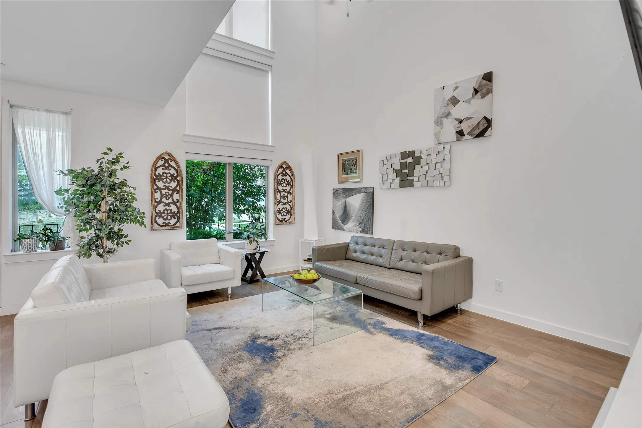 Two-story ceiling, tall windows, wood-finish flooring, and crisp white walls