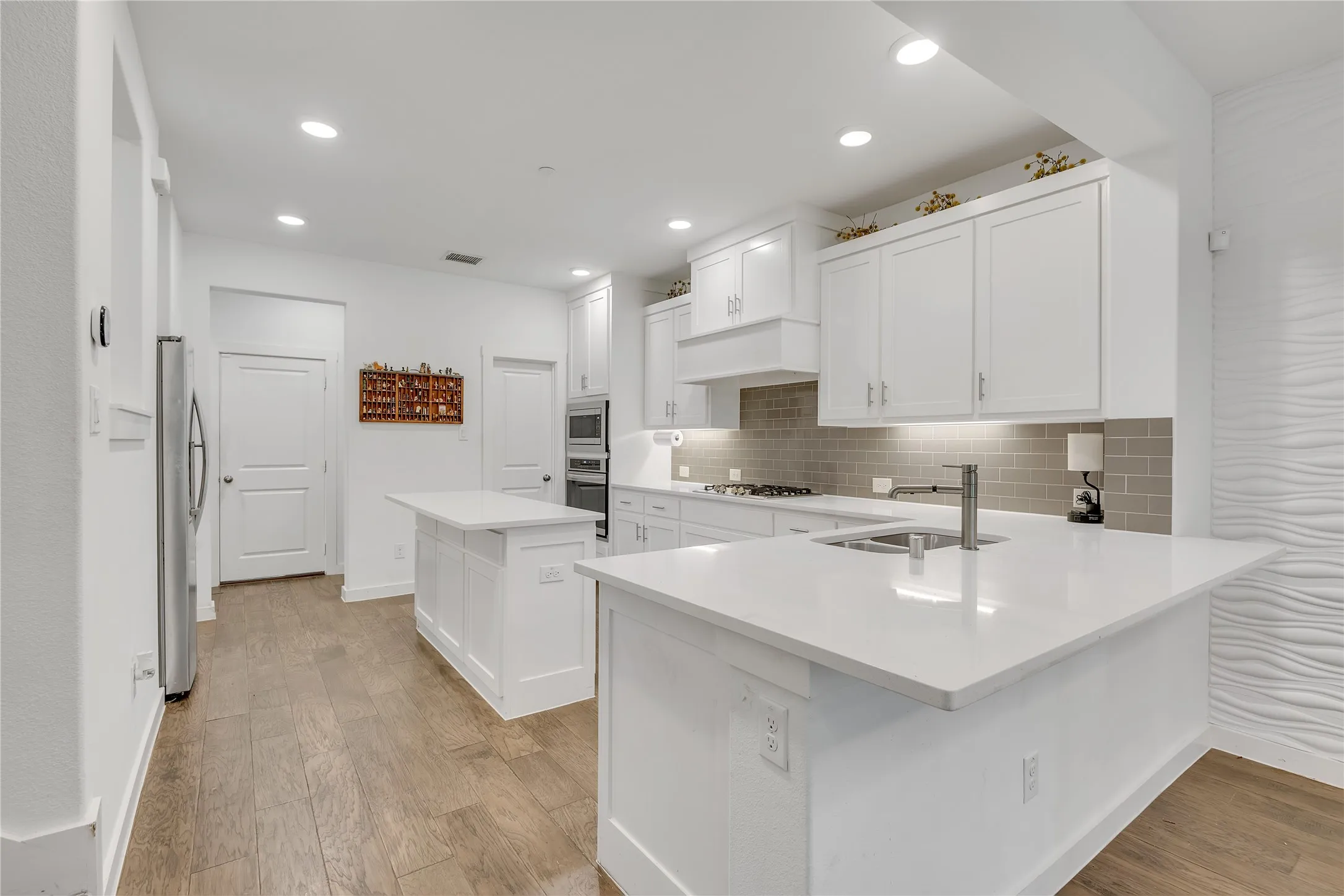 Kitchen featuring white cabinetry, light-toned wood-finish flooring, recessed lighting, and white countertops