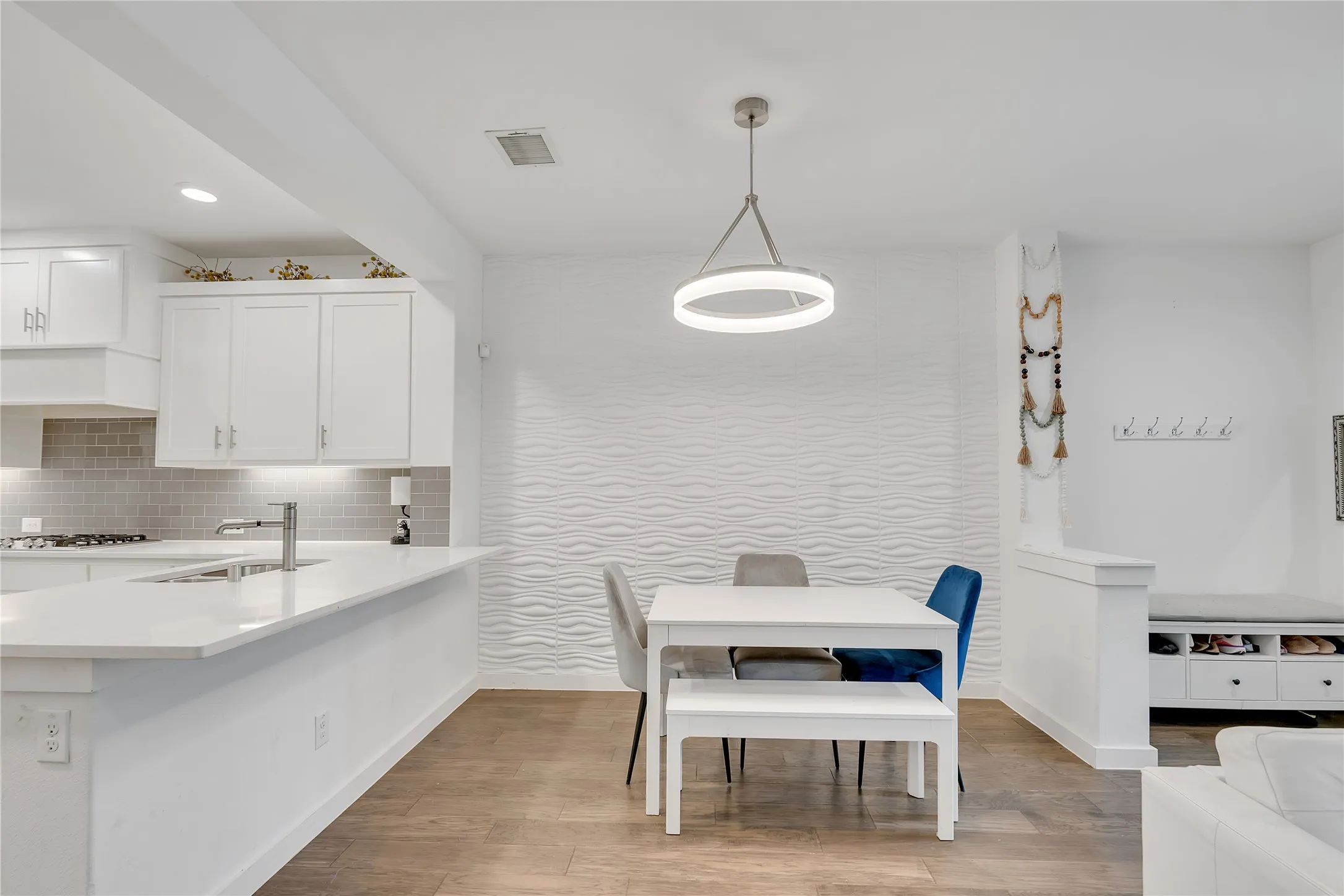 Kitchen and dining area featuring a breakfast bar with white countertops, white shaker cabinetry, and a tile backsplash