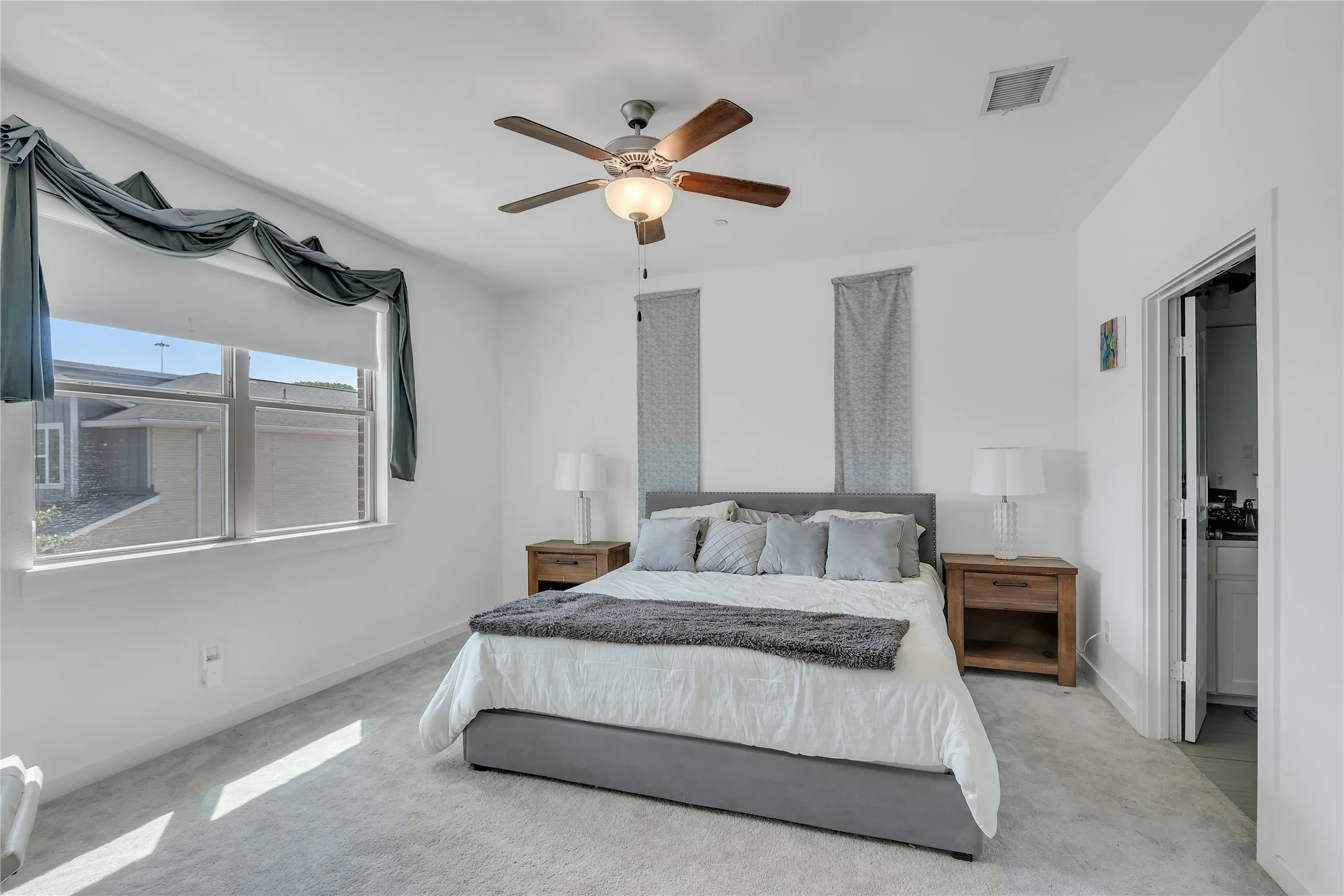 Plush carpeting, a modern ceiling fan, and a light-filled window