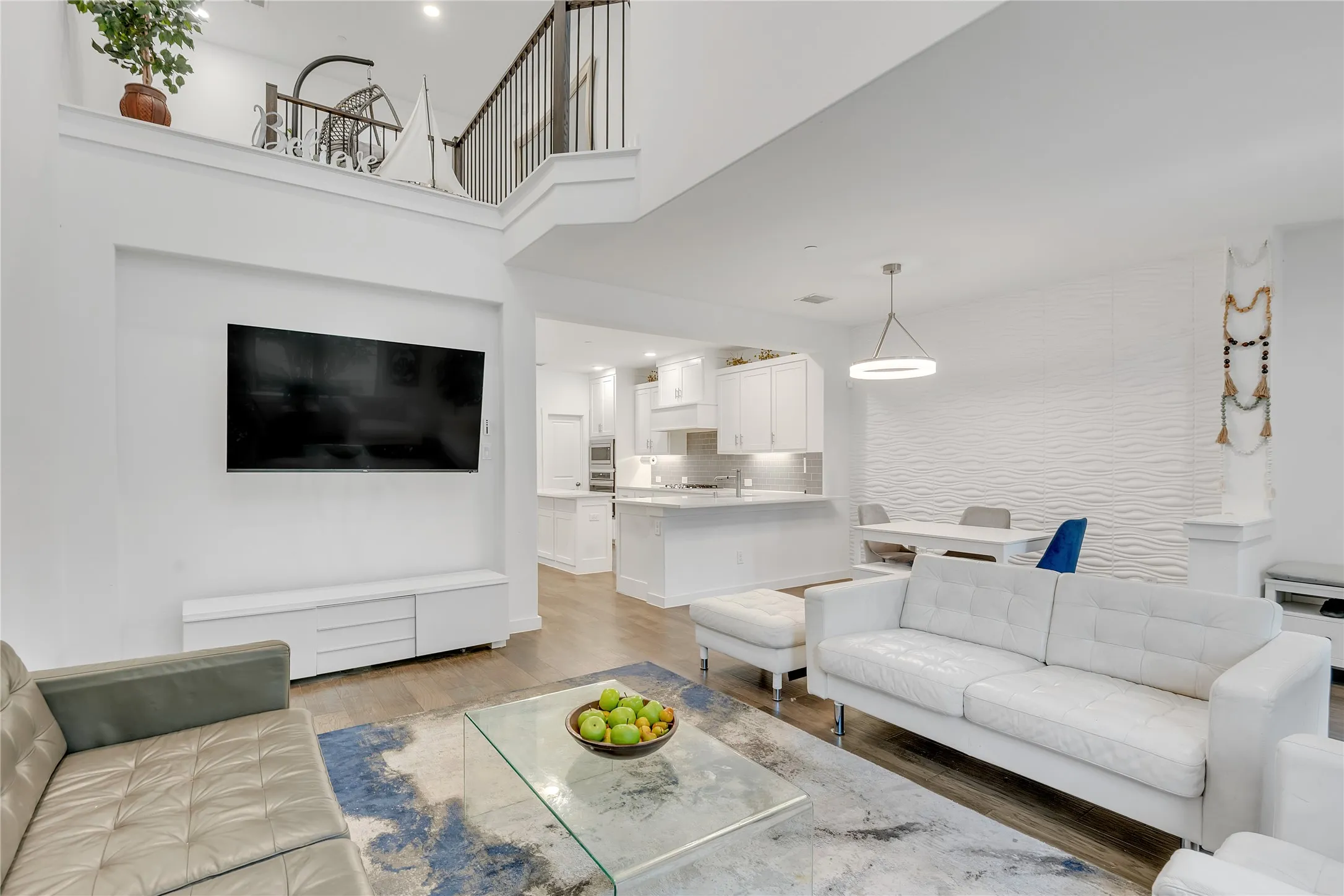 Open-concept living area with wood-finish flooring, a contemporary accent wall, and a built-in media console