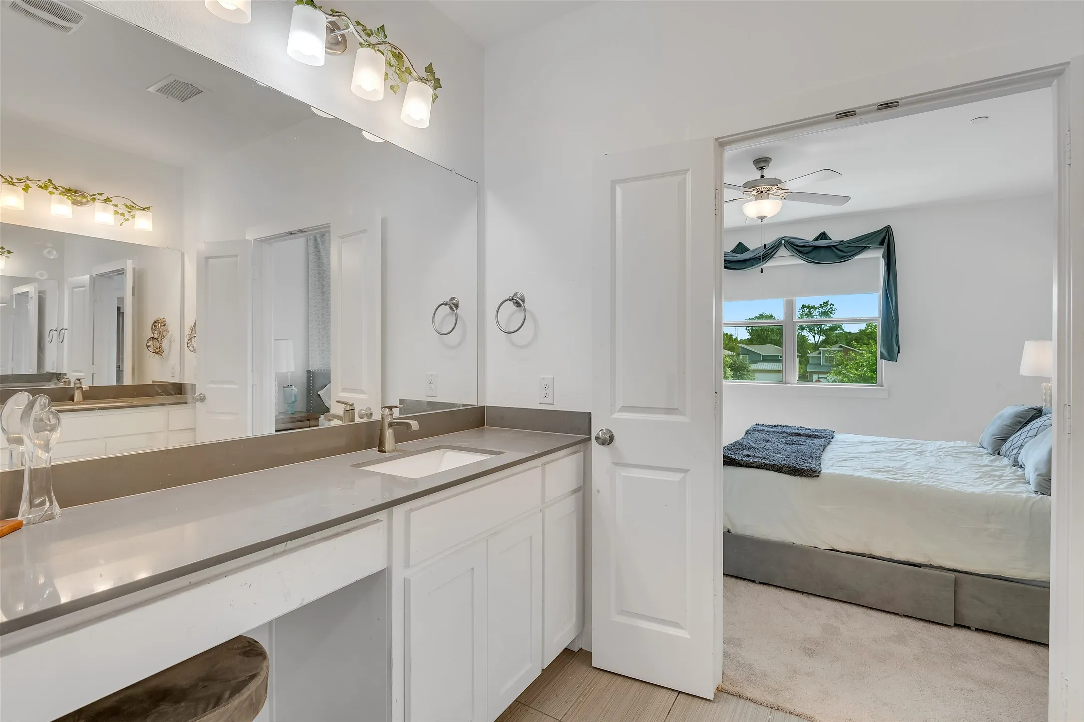 Expansive vanity featuring a single basin sink, brushed nickel faucet, large mirror, and ample under-counter storage