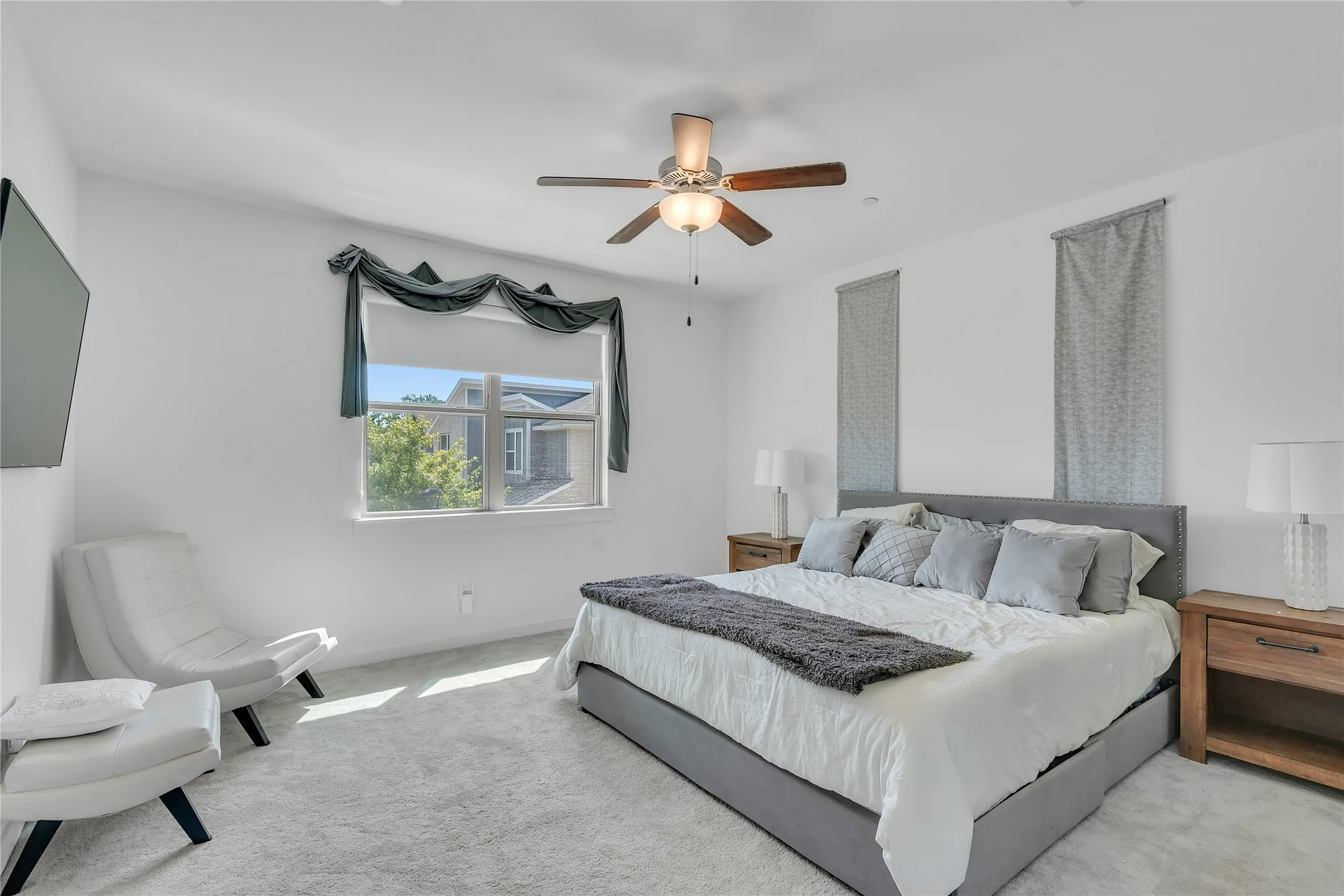 Recessed lighting, ceiling fan with light fixture, window with roller shade, and light-toned carpeting