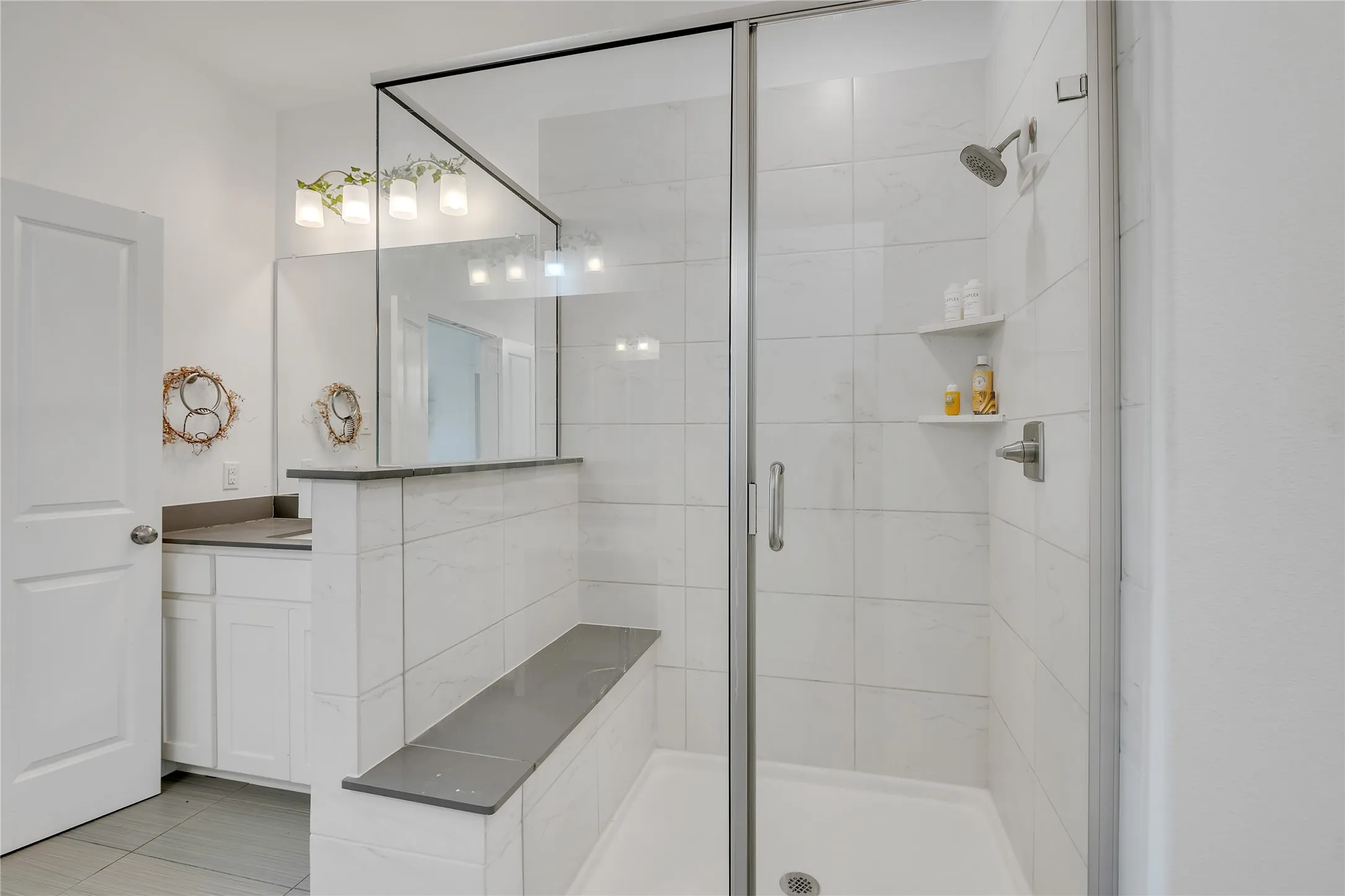 Glass-enclosed shower with a built-in bench and integrated shelving