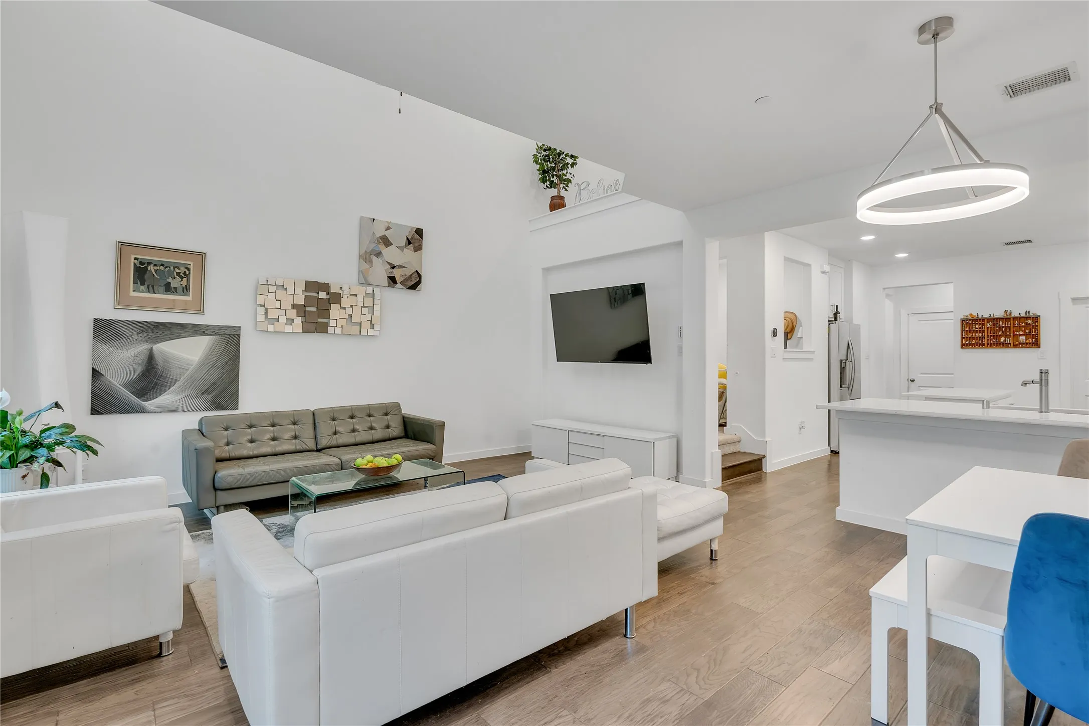 Spacious open-concept living area with high ceilings, wood-finish flooring, and recessed lighting