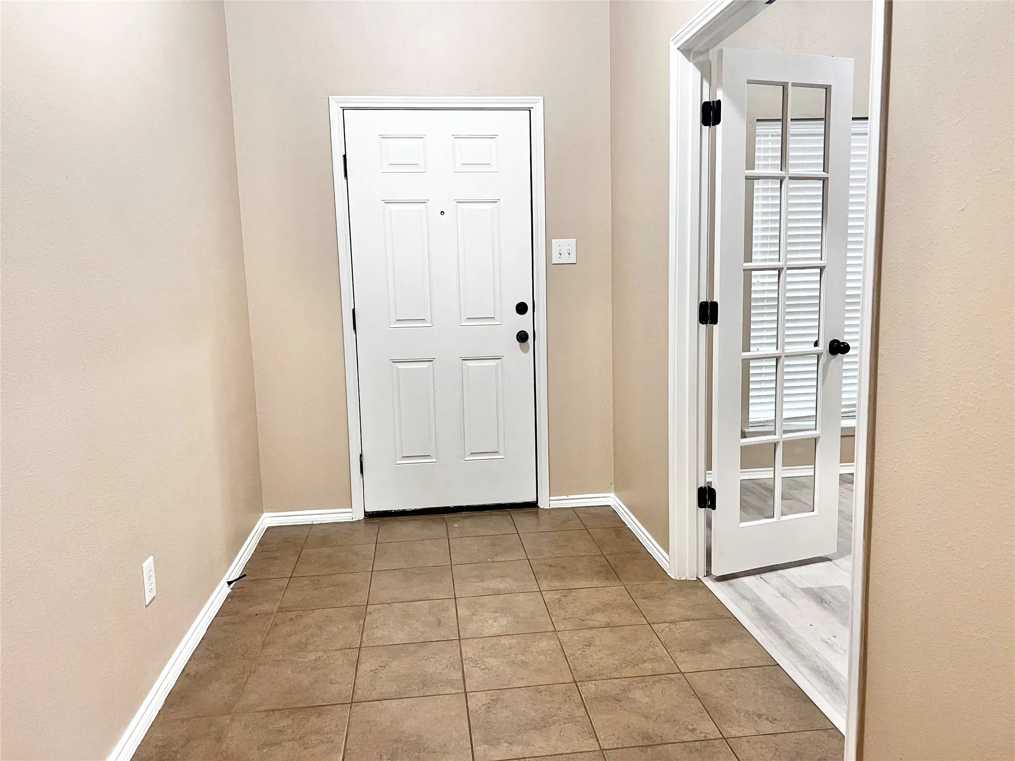 Tile flooring, paneled entry door, French doors, wood-finish flooring