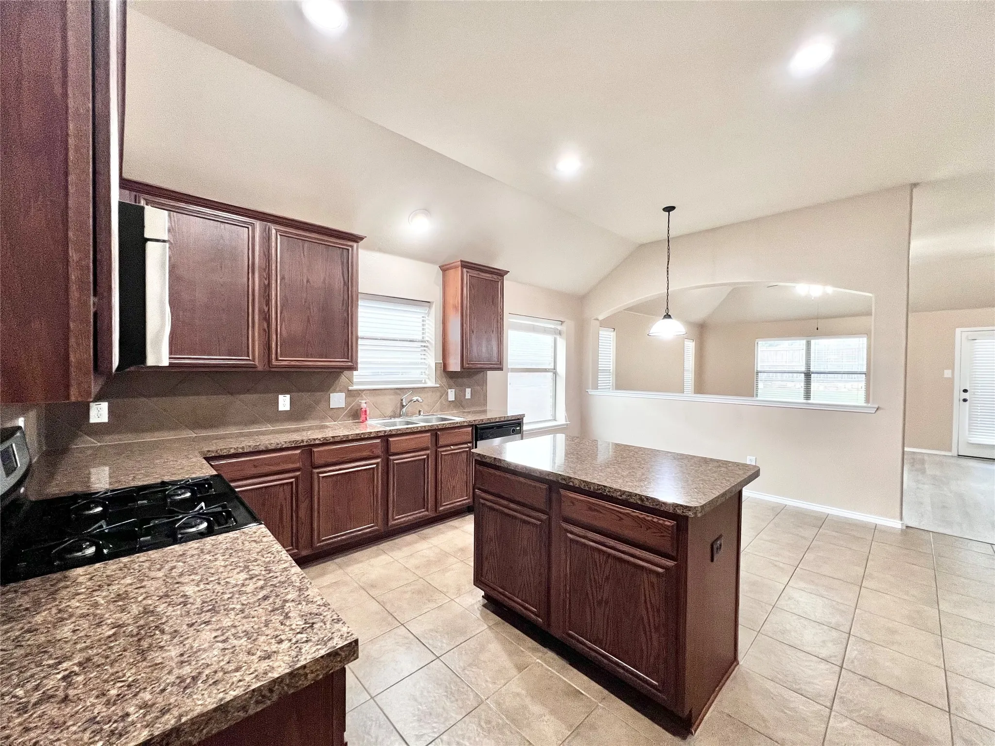 Kitchen featuring a central island, recessed lighting, tile flooring, wood cabinetry, and solid surface countertops