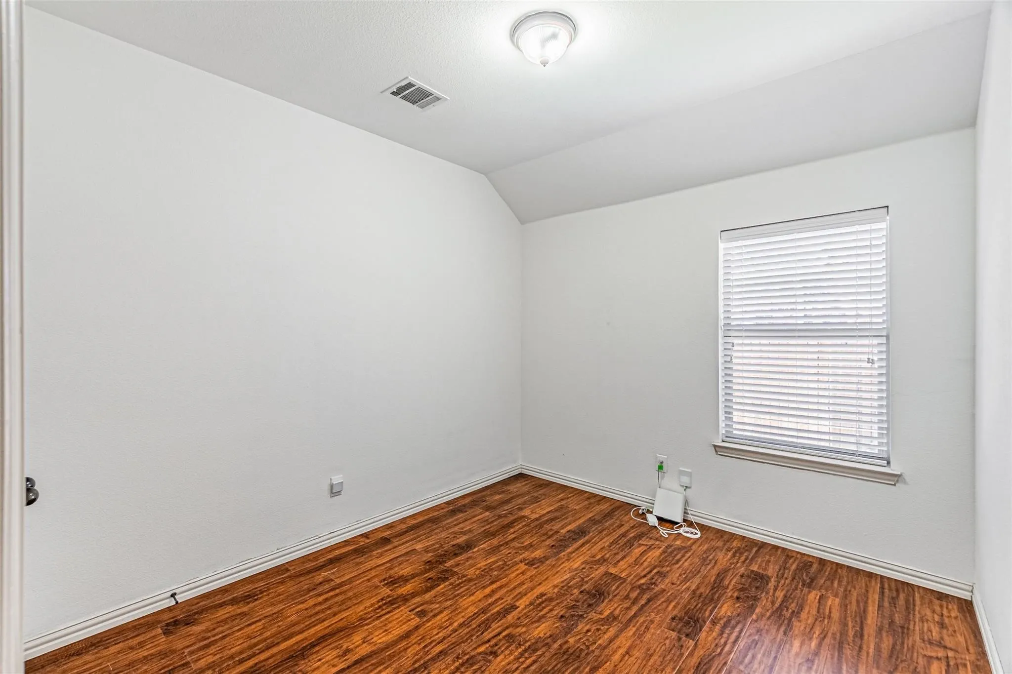Light-filled interior featuring wood-finish flooring, white walls, and a window with blinds