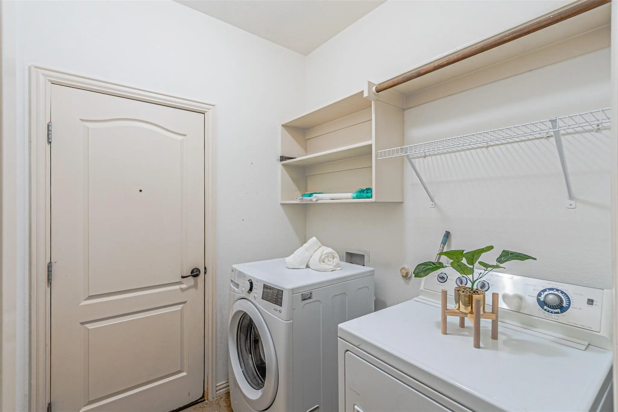 Laundry area featuring built-in shelving, a metal wire rack, and a mounted clothes rod
