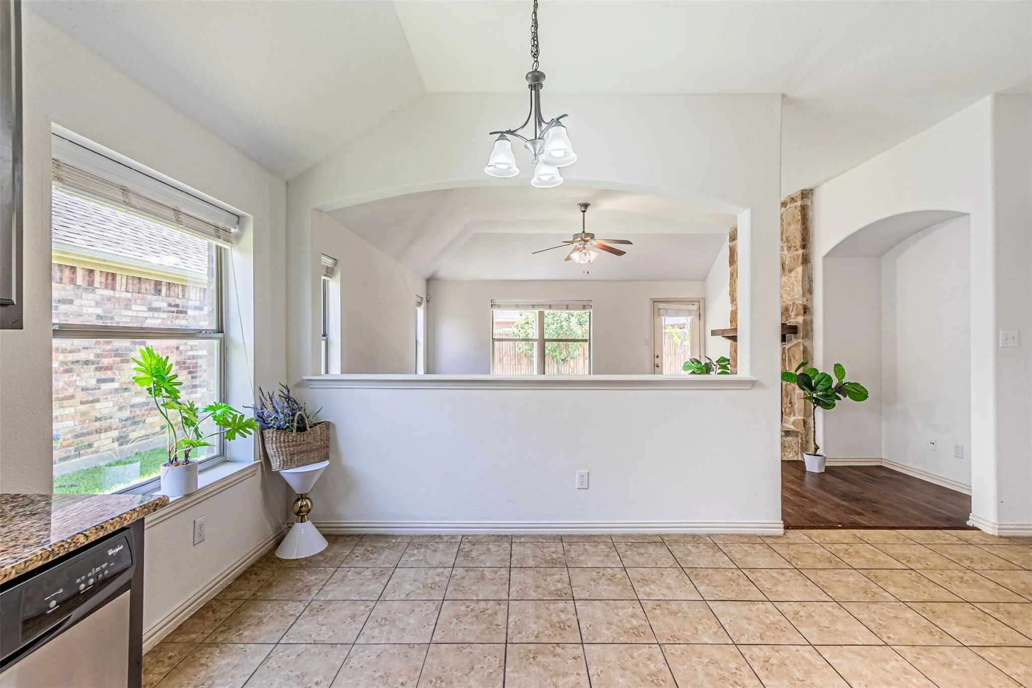 Vaulted ceiling with a chandelier, tile flooring, and a window with blinds
