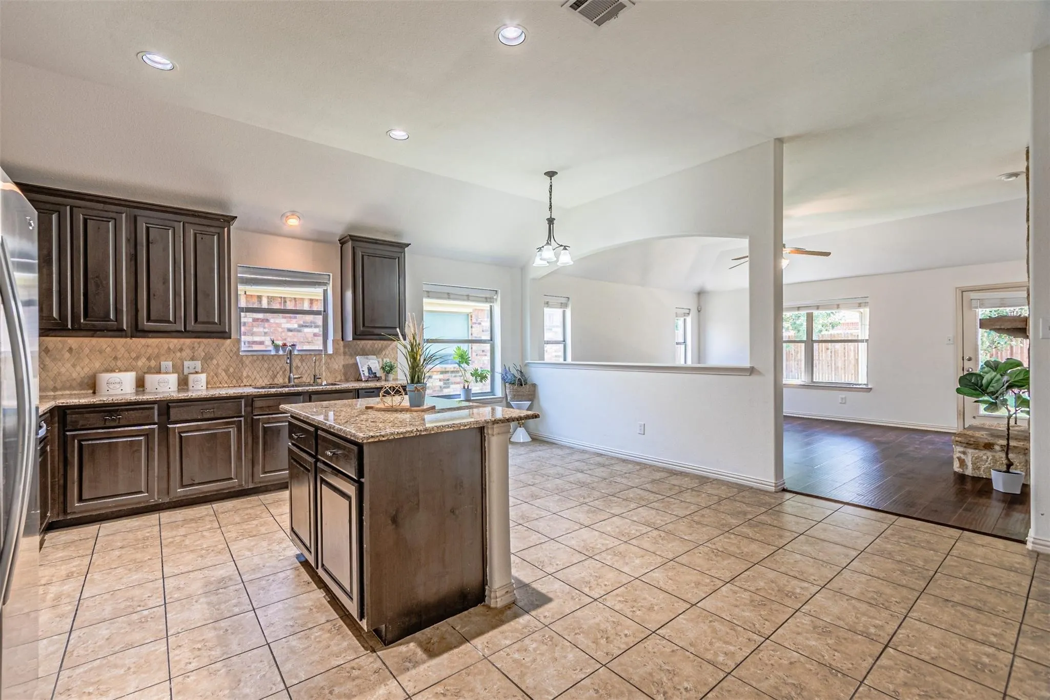Kitchen with dark wood cabinetry, a center island featuring a light-toned countertop, and recessed lighting