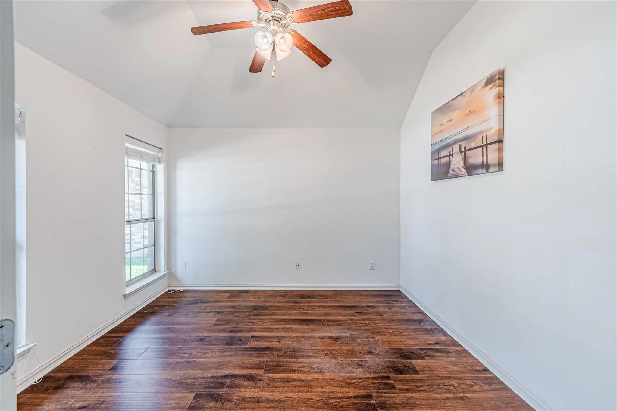 Vaulted ceiling, wood-finish flooring, ceiling fan, and a single window