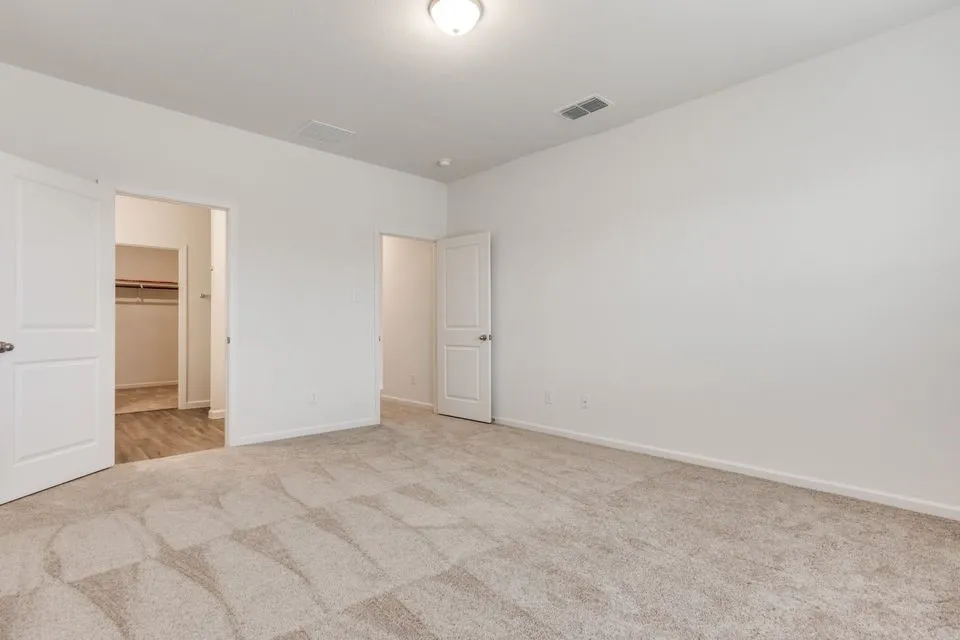 Expansive room with neutral carpeting, white walls, and a ceiling-mounted light fixture