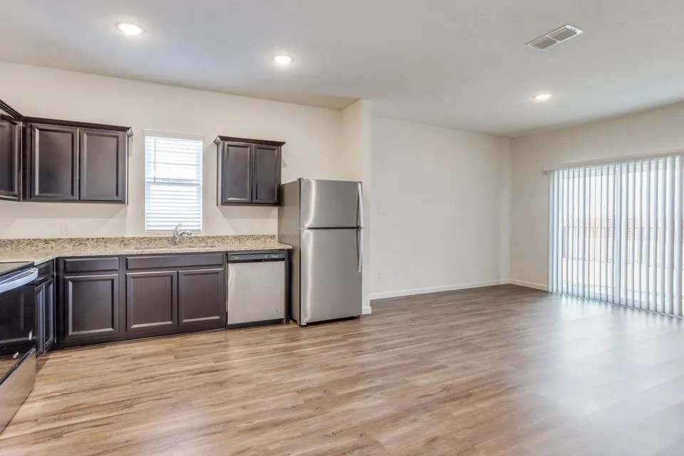 Open-concept living area featuring wood-finish flooring, recessed lighting, and a sliding glass door