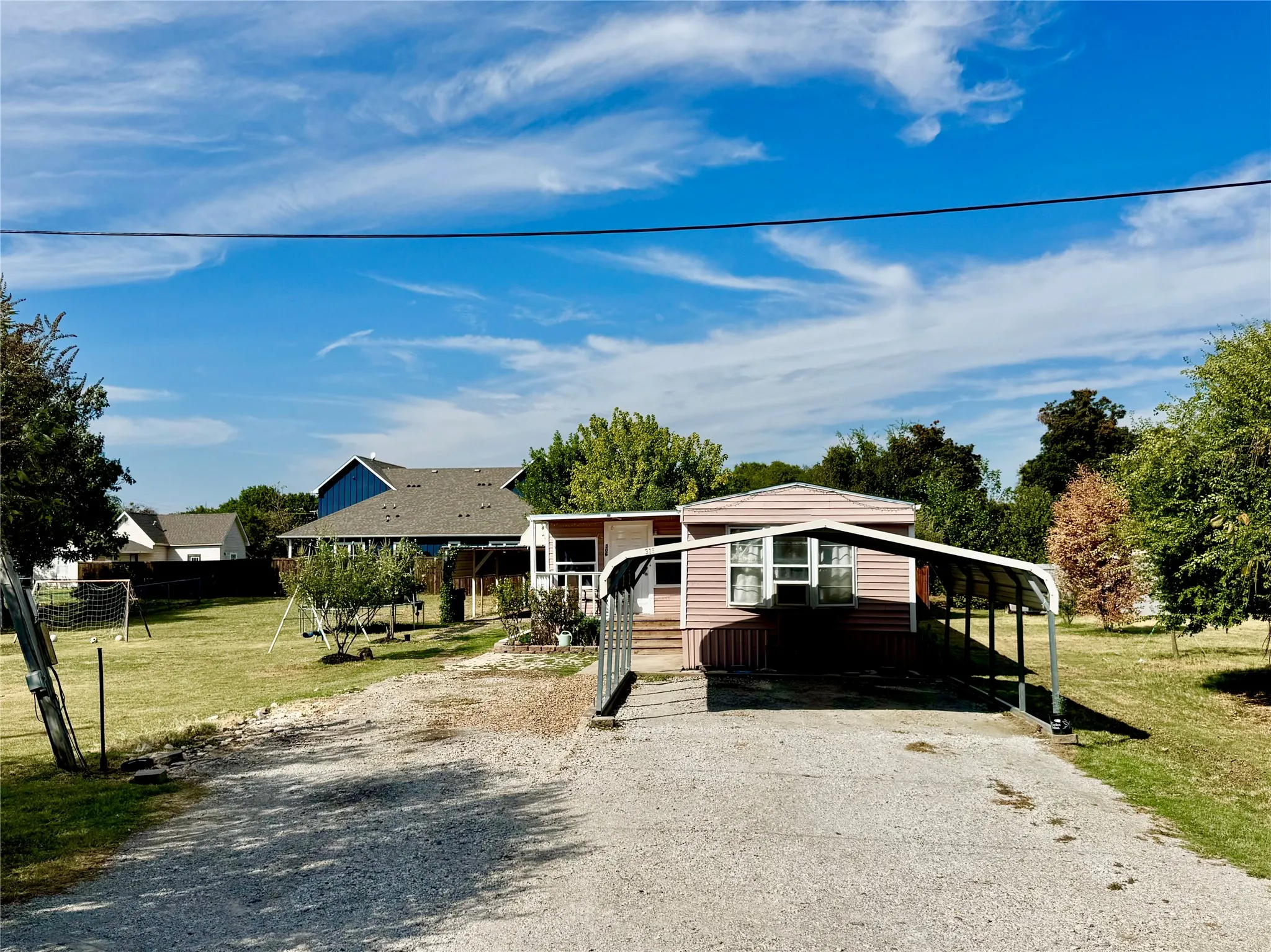 Gravel driveway leading to a metal carport